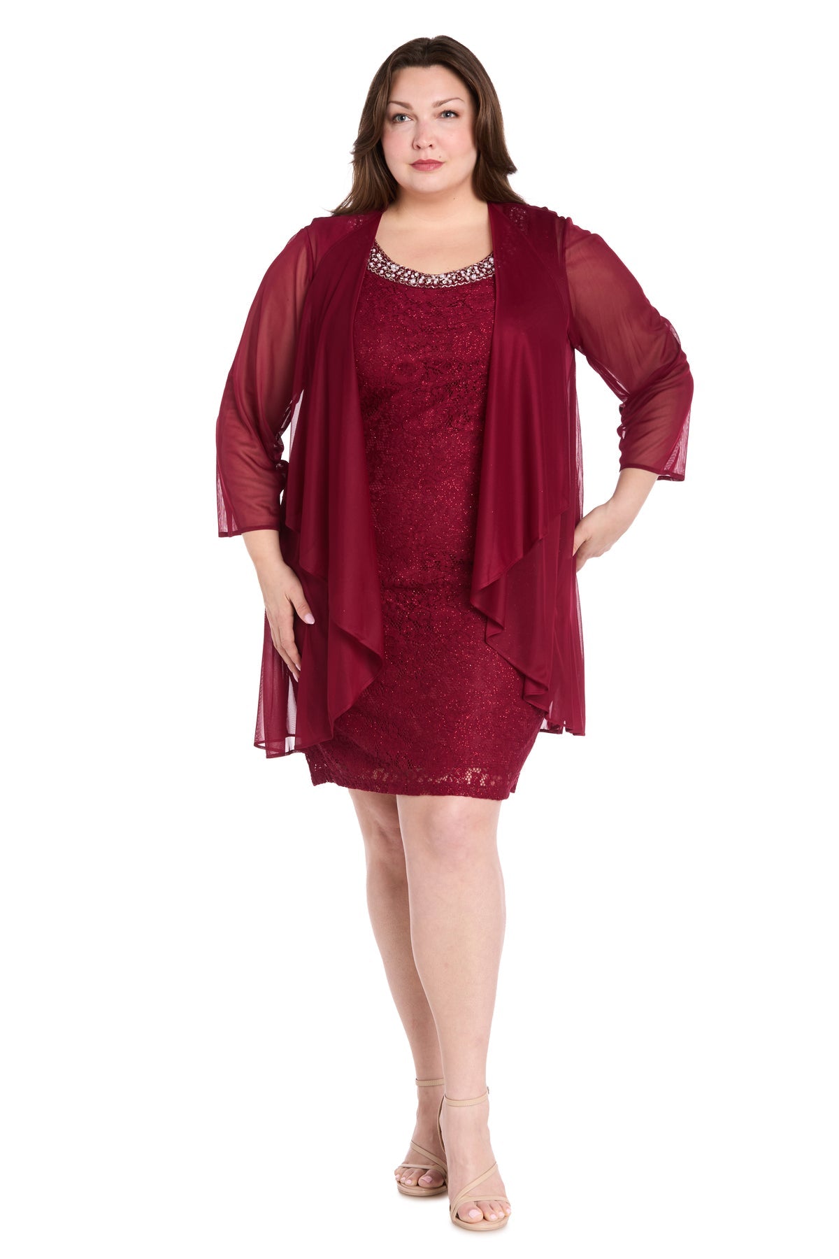 A woman models the Plus-Size Short Jacket Dress: R&M Richards 3594W, featuring a knee-length lace dress with a matching sheer overlay, standing forward against a white background in nude heels.