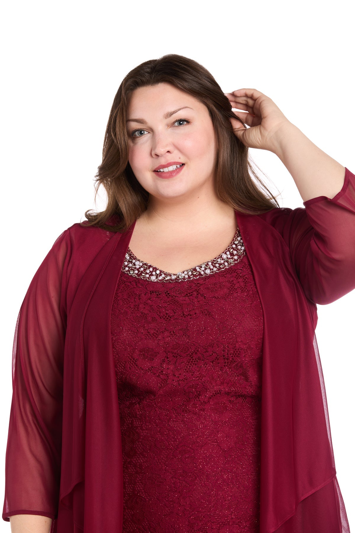 Woman with long brown hair wears the R&M Richards 3594W Plus-Size Short Jacket Dress, a burgundy lace party style with a sheer overlay, posing with one hand in her hair against a plain white background.