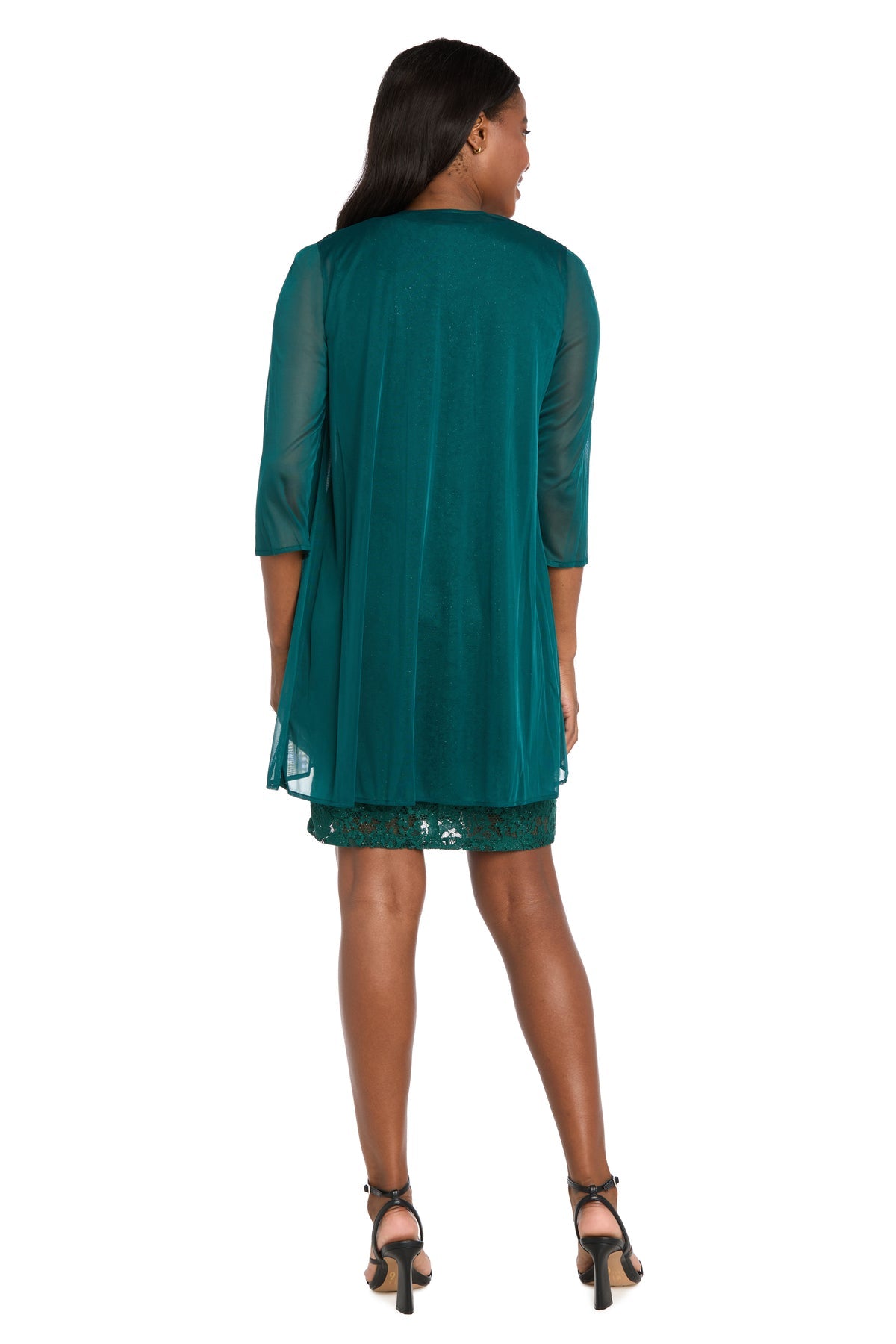 A woman stands facing away, wearing the R&M Richards 3594 short semi-formal lace jacket dress in teal with a sheer overlay and black heeled sandals, set against a white background.