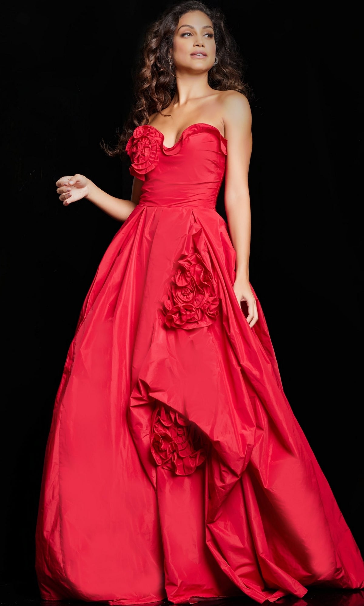 A woman in the Long Prom Dress 37266 by Jovani—an elegant, strapless, floor-length red gown with floral embellishments—stands against a black background.