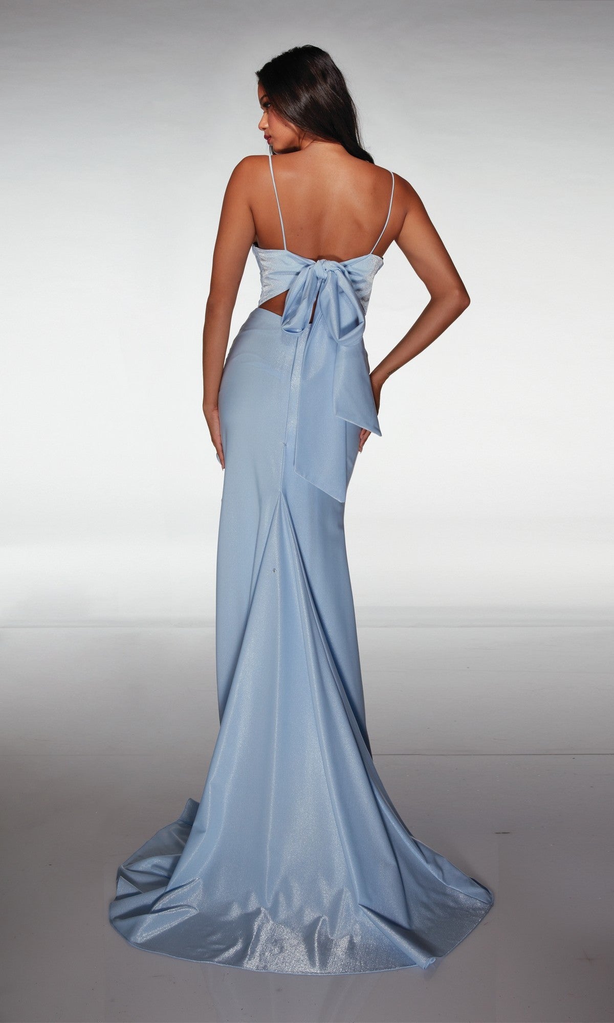 Woman wearing the Aerie Couture 372 Long Prom Dress in light blue, featuring spaghetti straps, an open back, and a large bow detail, standing and facing away from the camera.