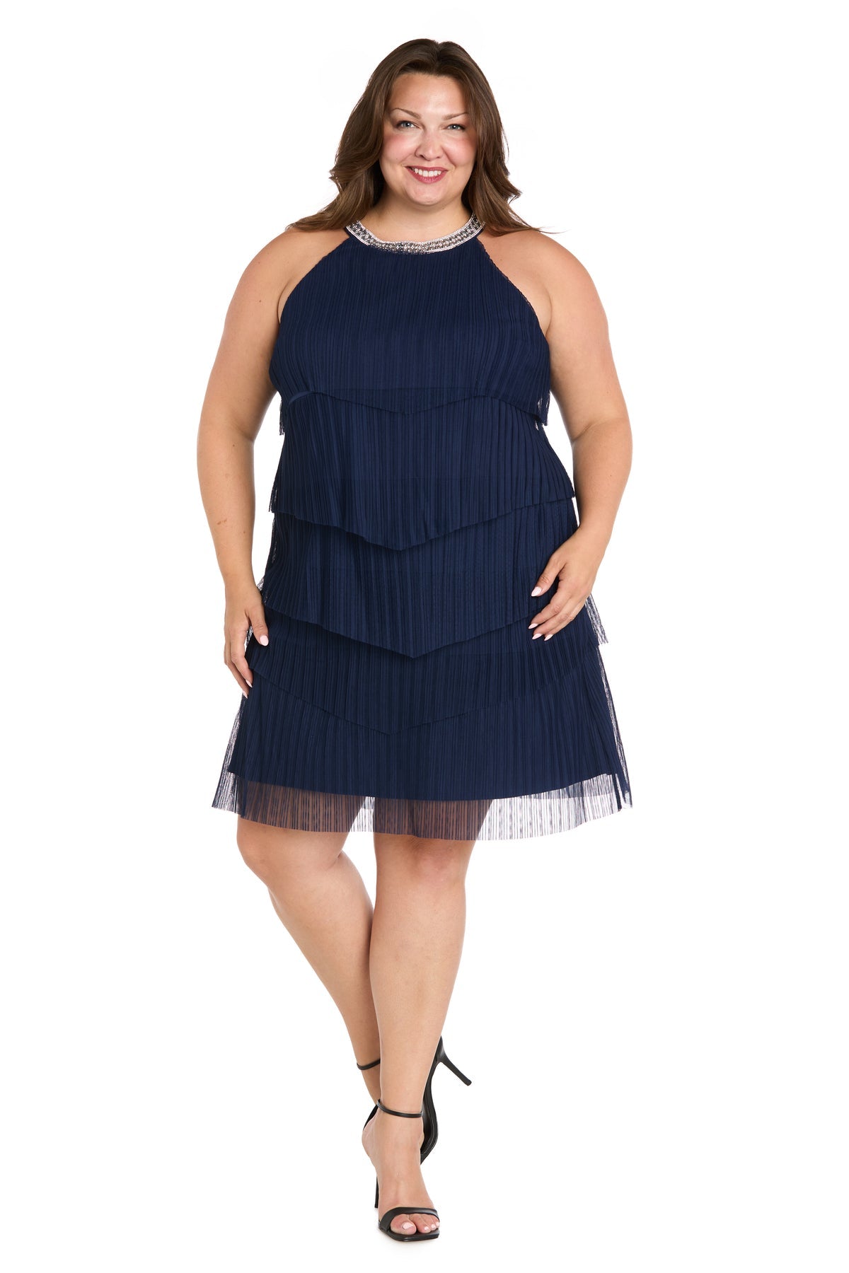 A woman in the R&M Richards 3744W plus-size navy party dress and black high-heeled sandals stands against a white background.