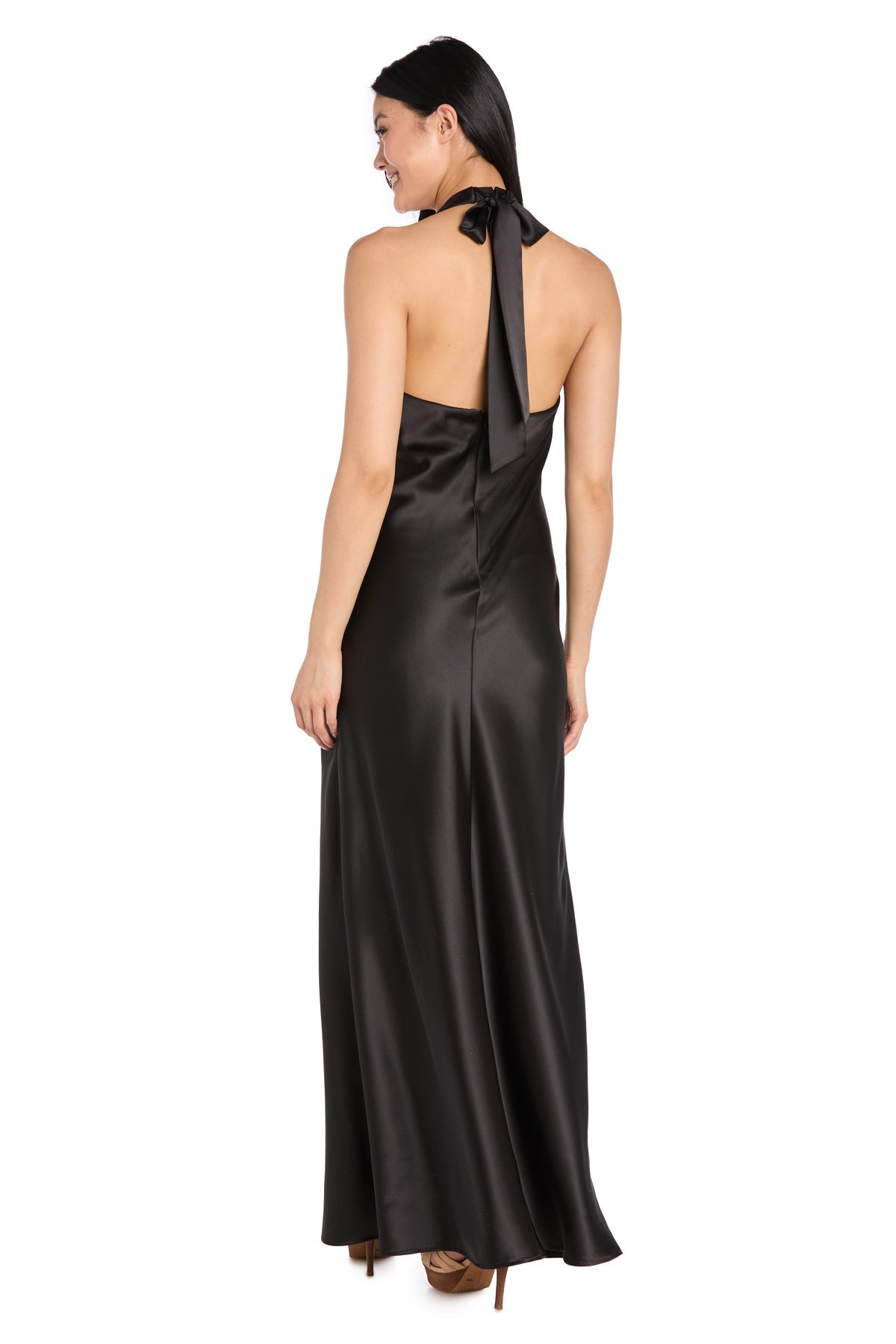 A woman smiles while facing away, wearing the R&M Richards 3773 Black Satin Halter Formal Dress with a back bow—ideal for black-tie events—against a white backdrop.