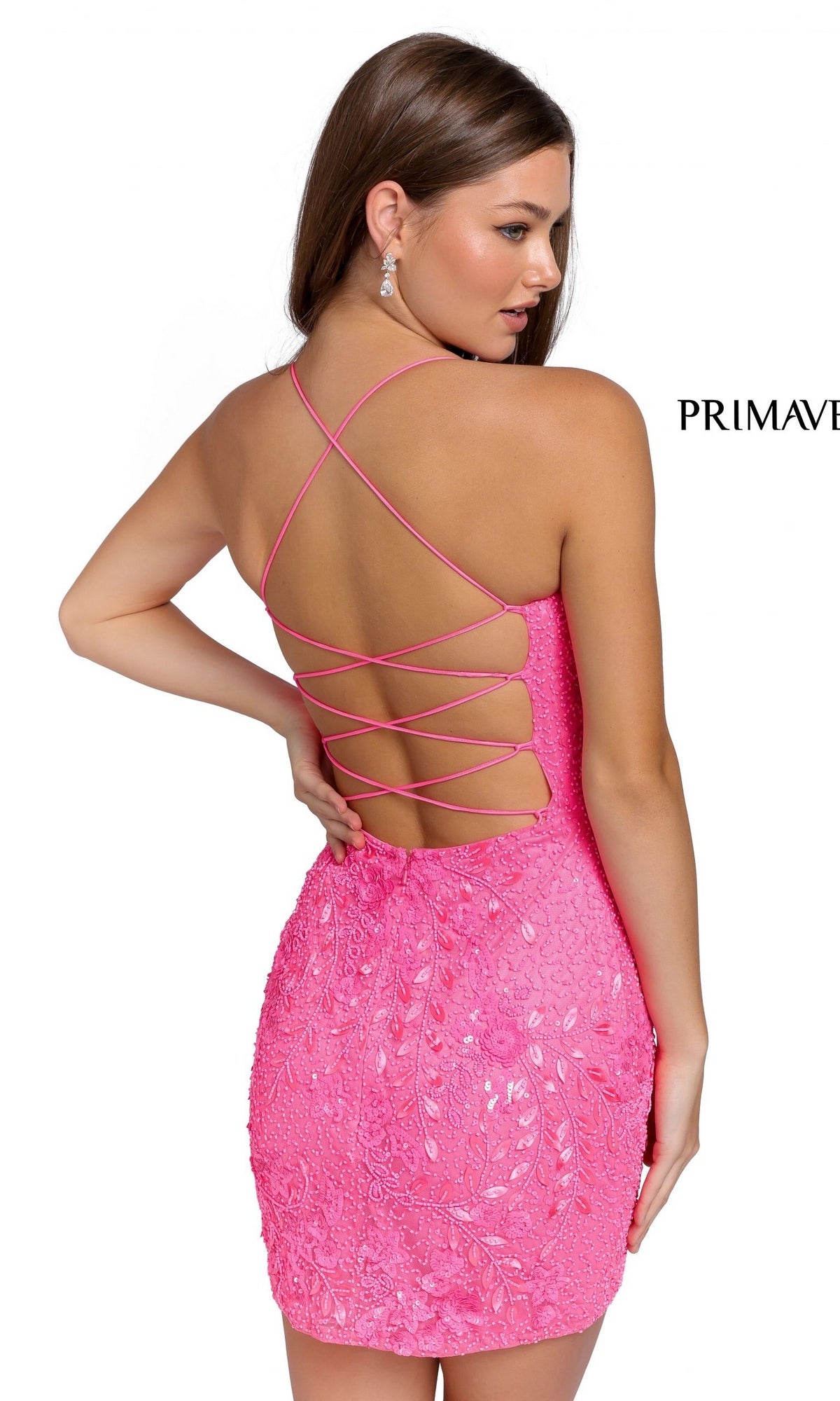 A woman models the Strappy-Back Short Beaded Mini Party Dress 3816 in pink, featuring sequined fabric and crisscross straps, posing with her back to the camera against a plain white background.
