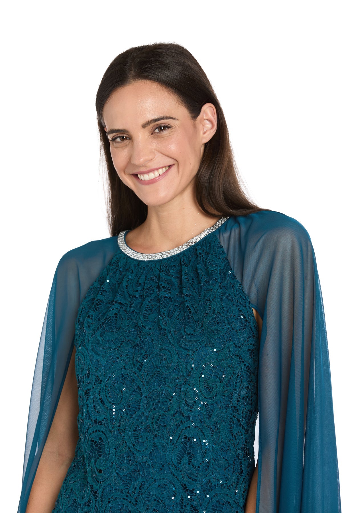 A woman with long brown hair smiles in the R&M Richards 3864 Knee-Length Cape Party Dress, featuring sheer sleeves and a decorative neckline, posing against a plain white background.