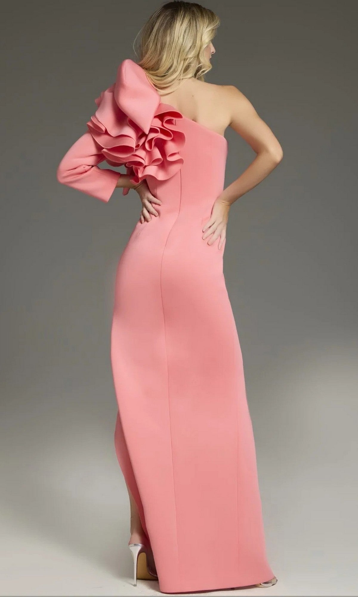 Woman in the Jovani 38928 long formal dress, a designer one-shoulder gown featuring a floor-length silhouette and ruffled sleeve detail, standing and facing away in high heels.