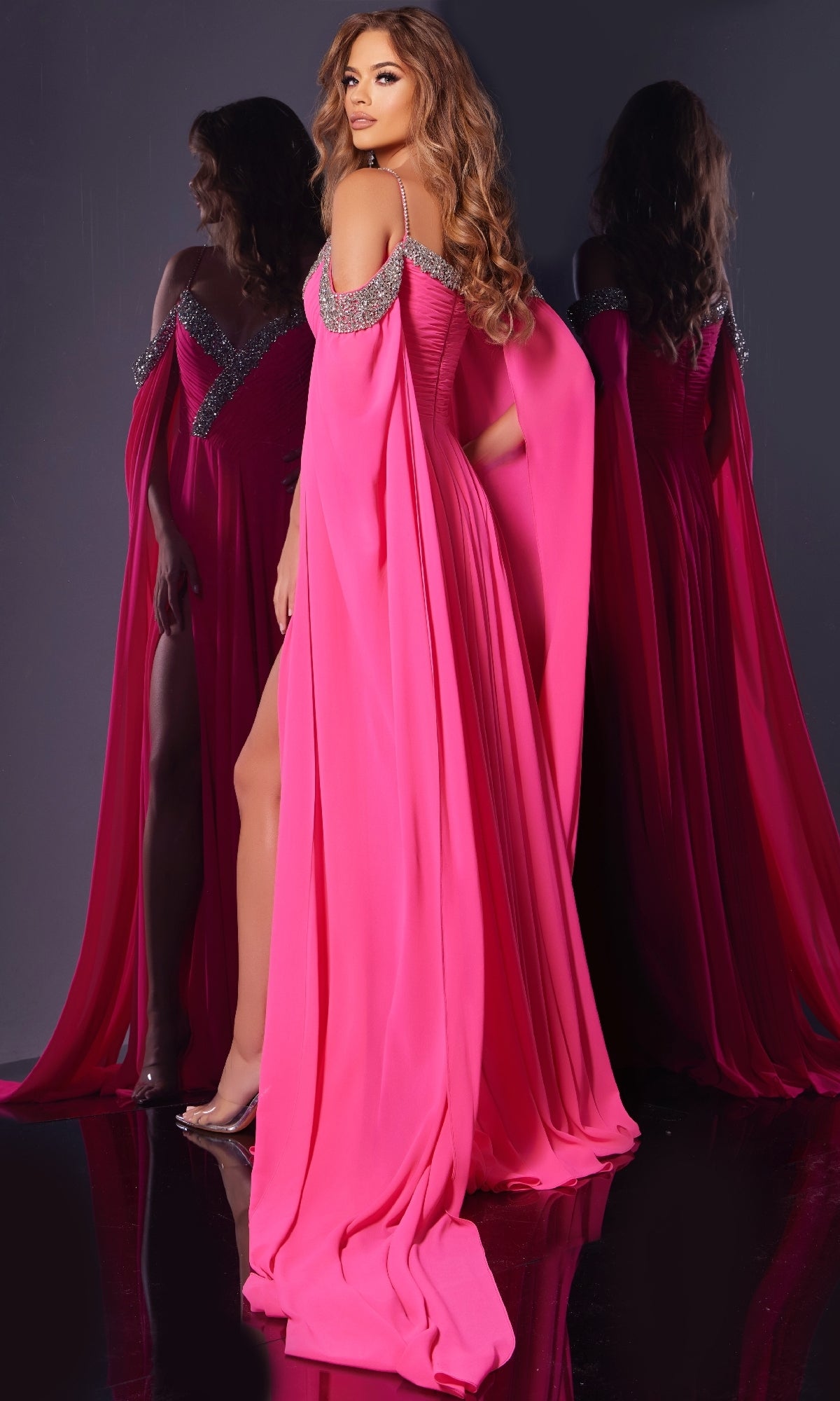 A woman poses in front of a mirror wearing the Jovani 38996 Long Formal Dress, featuring a bright pink hue, off-shoulder design with embellished straps and elegant draped sleeves.