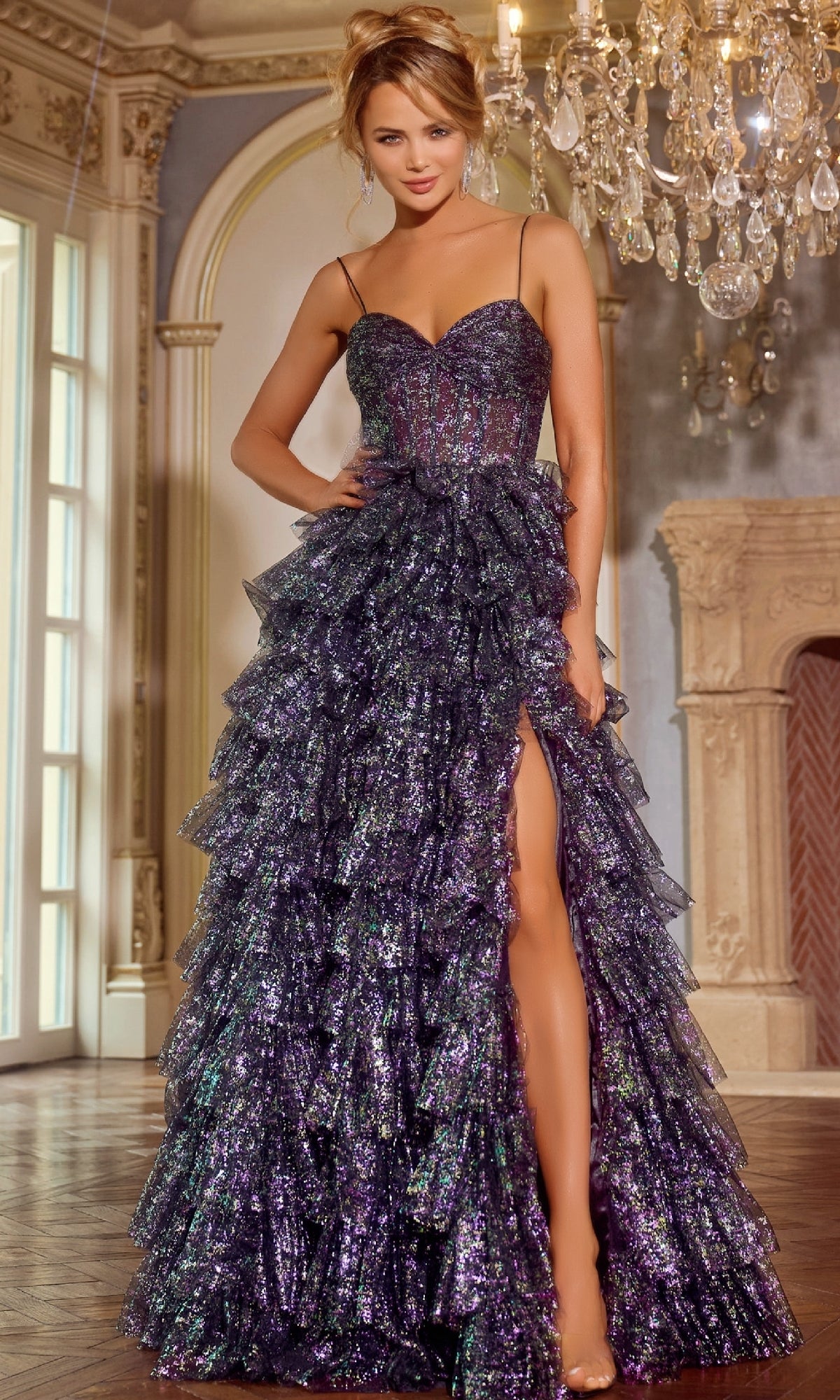In a formal setting, a woman wears the Jovani 39305 Ruffled Glitter-Tulle Prom Ball Gown in shimmering purple, standing near a chandelier and ornate fireplace.