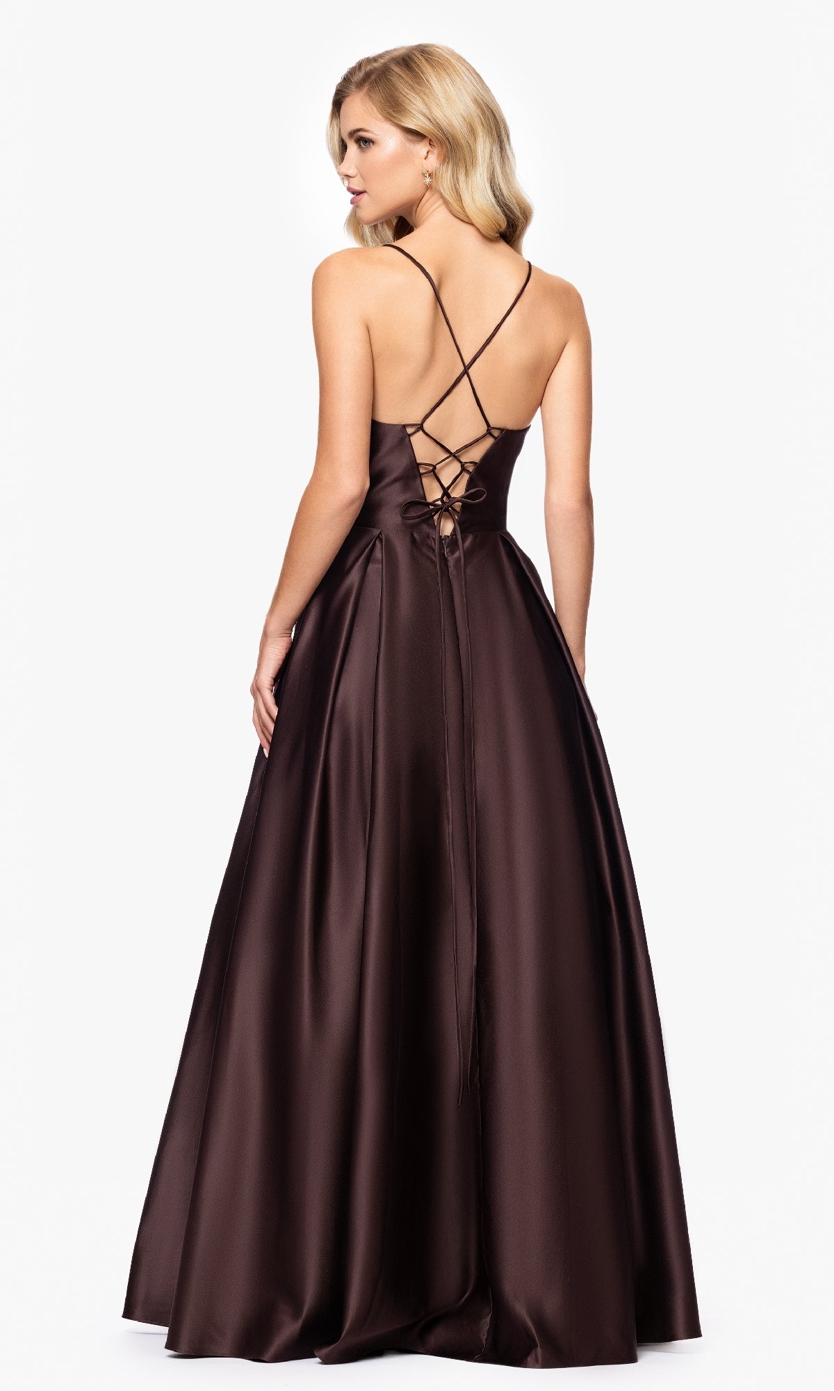 A woman in the Blondie Nites 3946BN long A-line prom dress featuring brown satin, a corset waist, lace-up open back, and spaghetti straps stands against a plain white background.