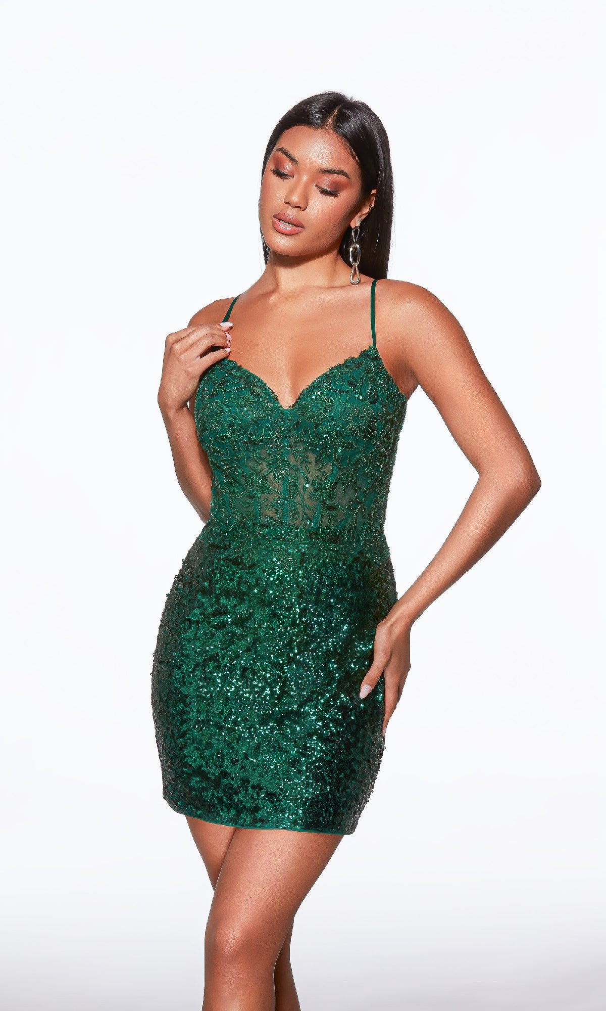 Woman wearing the Pine Green Short Sequin Hoco Dress: Alyce 40034, a sparkly short party dress with thin straps, standing against a plain white background.