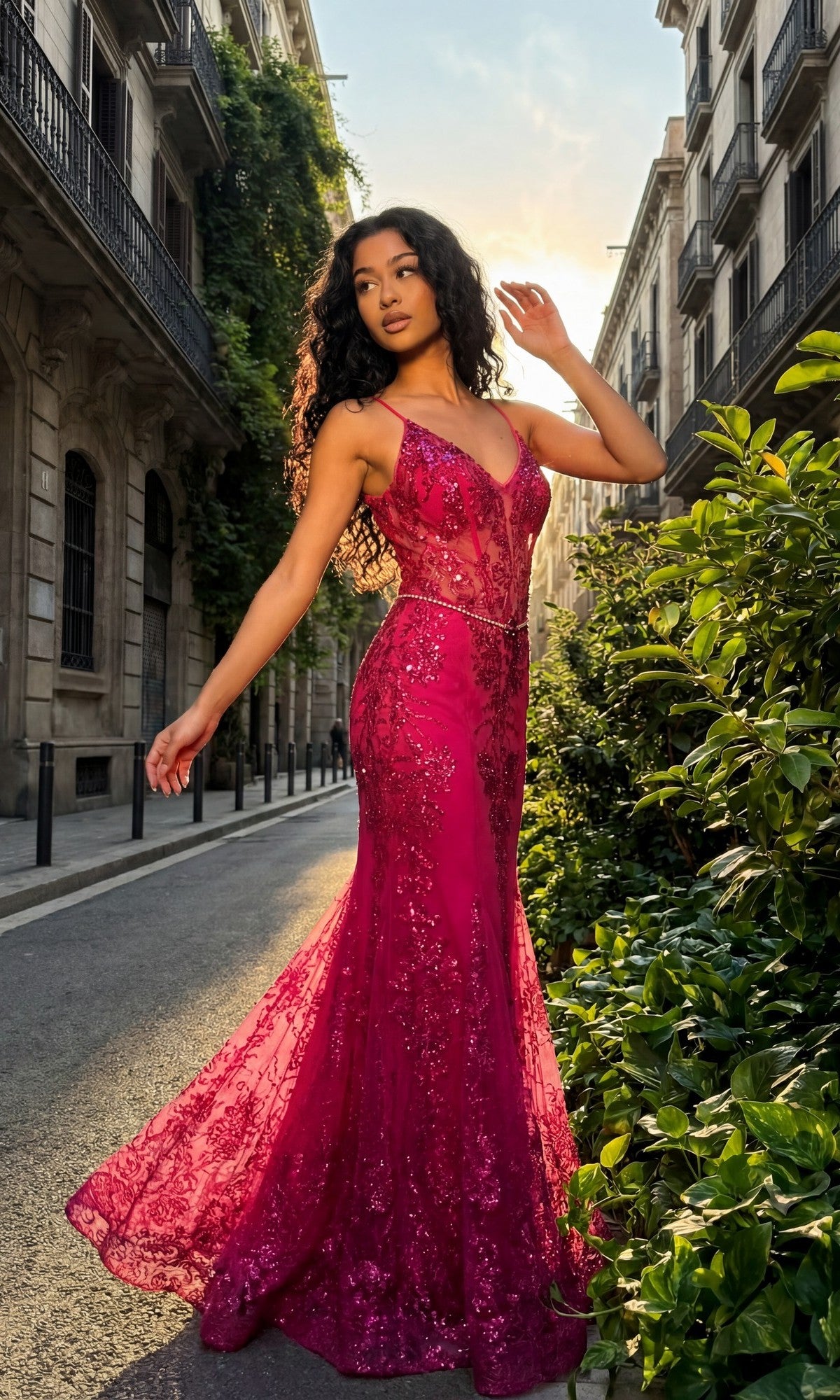 A woman wears the Chicas 4030 Long Prom Dress in fuchsia, a fitted, floor-length gown with sparkling embellishments, as she stands on a greenery-lined city street with sunlight shining behind her.