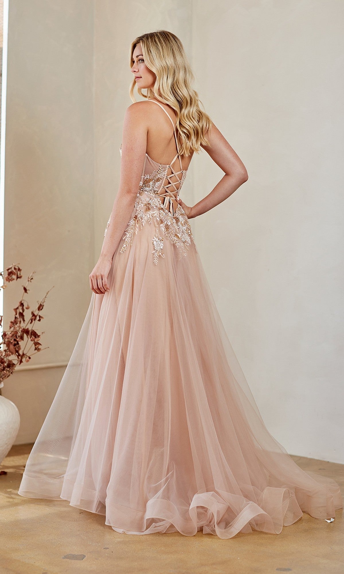 A woman stands indoors in a floor-length purple Amelia Couture 4064 prom gown with a lace-up back, embodying a dreamy twist on the classic a-line dress.