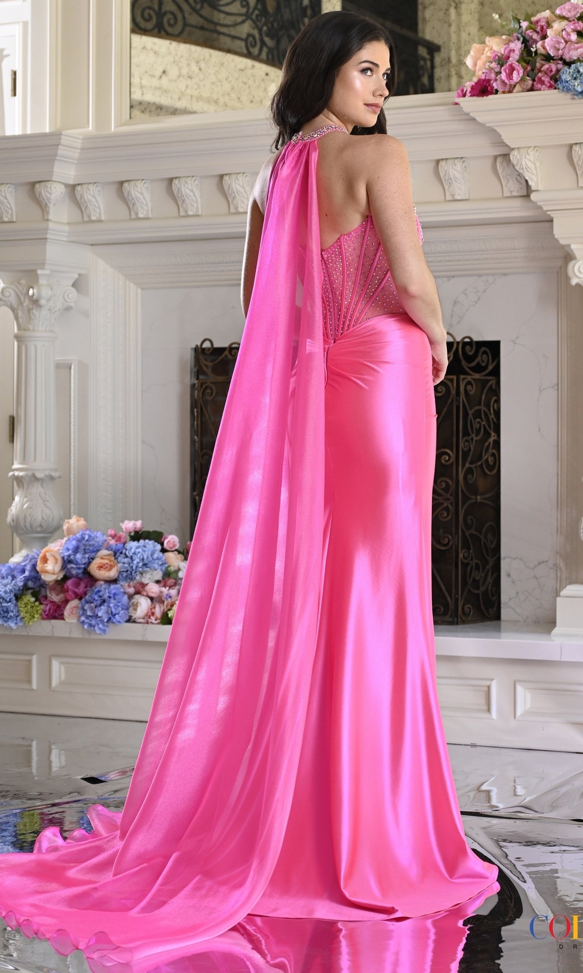 Colors Dress 4067 is a bright pink corset prom dress featuring rhinestone-embellished straps and a long, flowing choker cape.