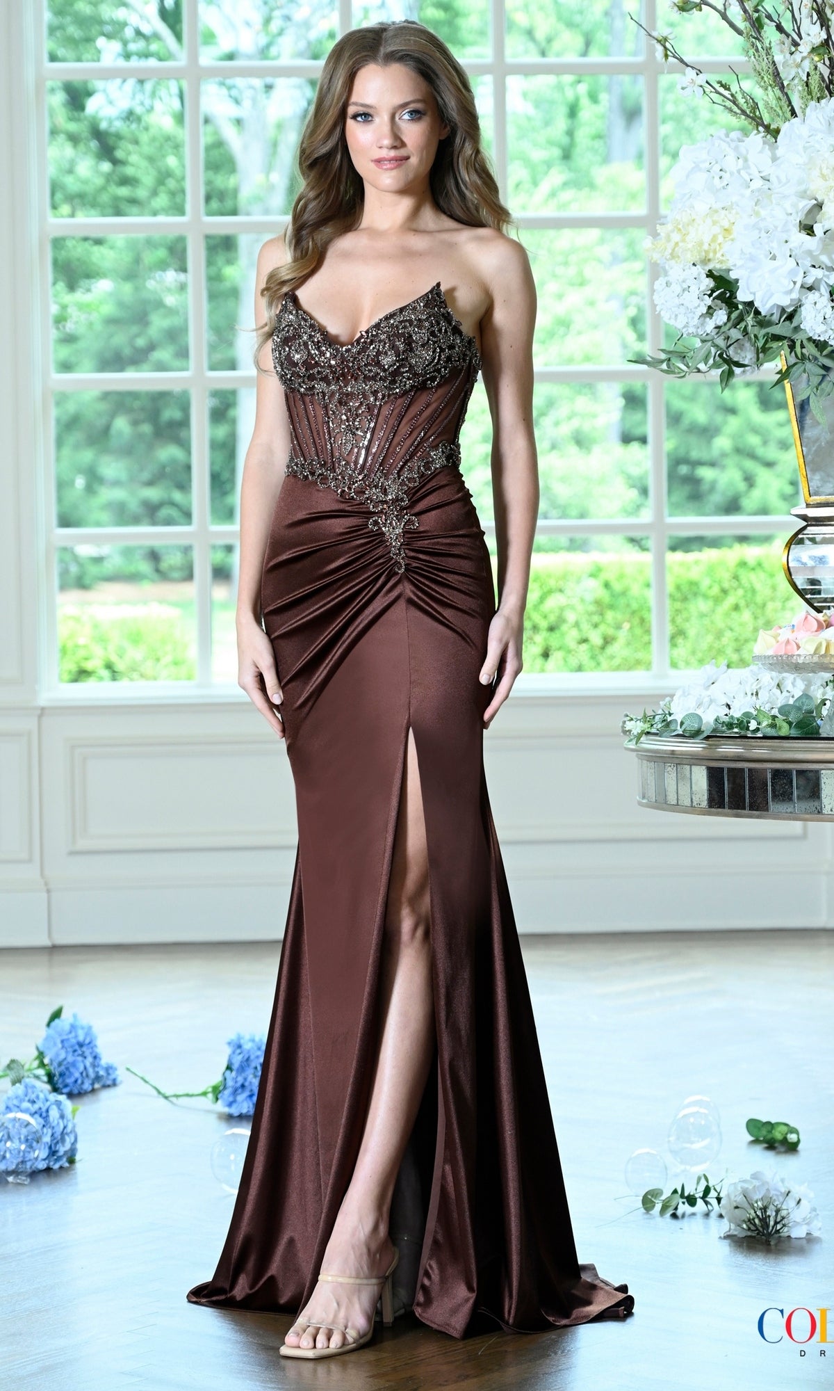A strapless brown Colors Dress 4135 corset prom dress featuring a beaded bodice and a high thigh slit.