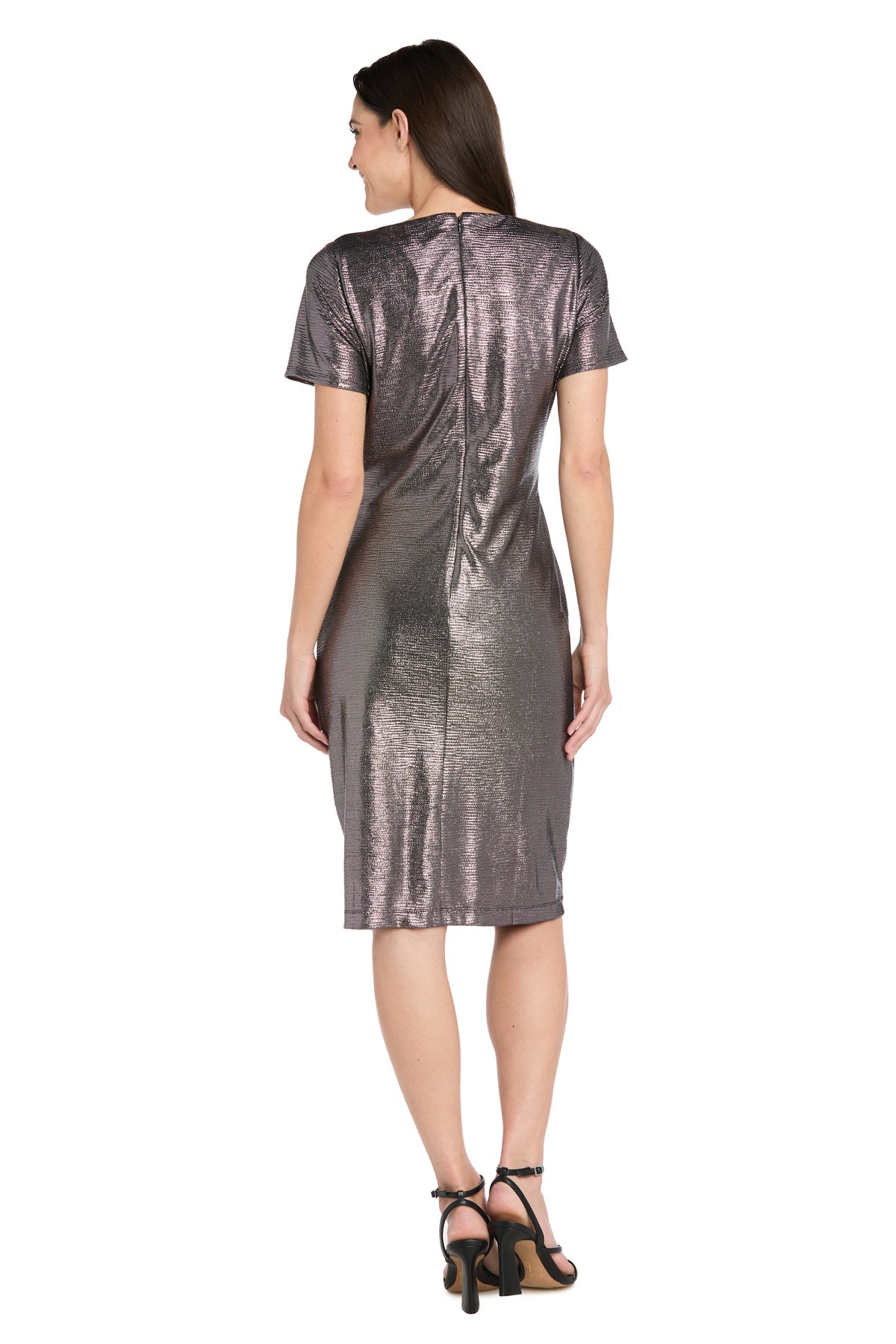 A woman stands facing away, wearing the R&M Richards 4177 short metallic cocktail dress with short sleeves and a knee-length hem, paired with black high-heeled sandals.
