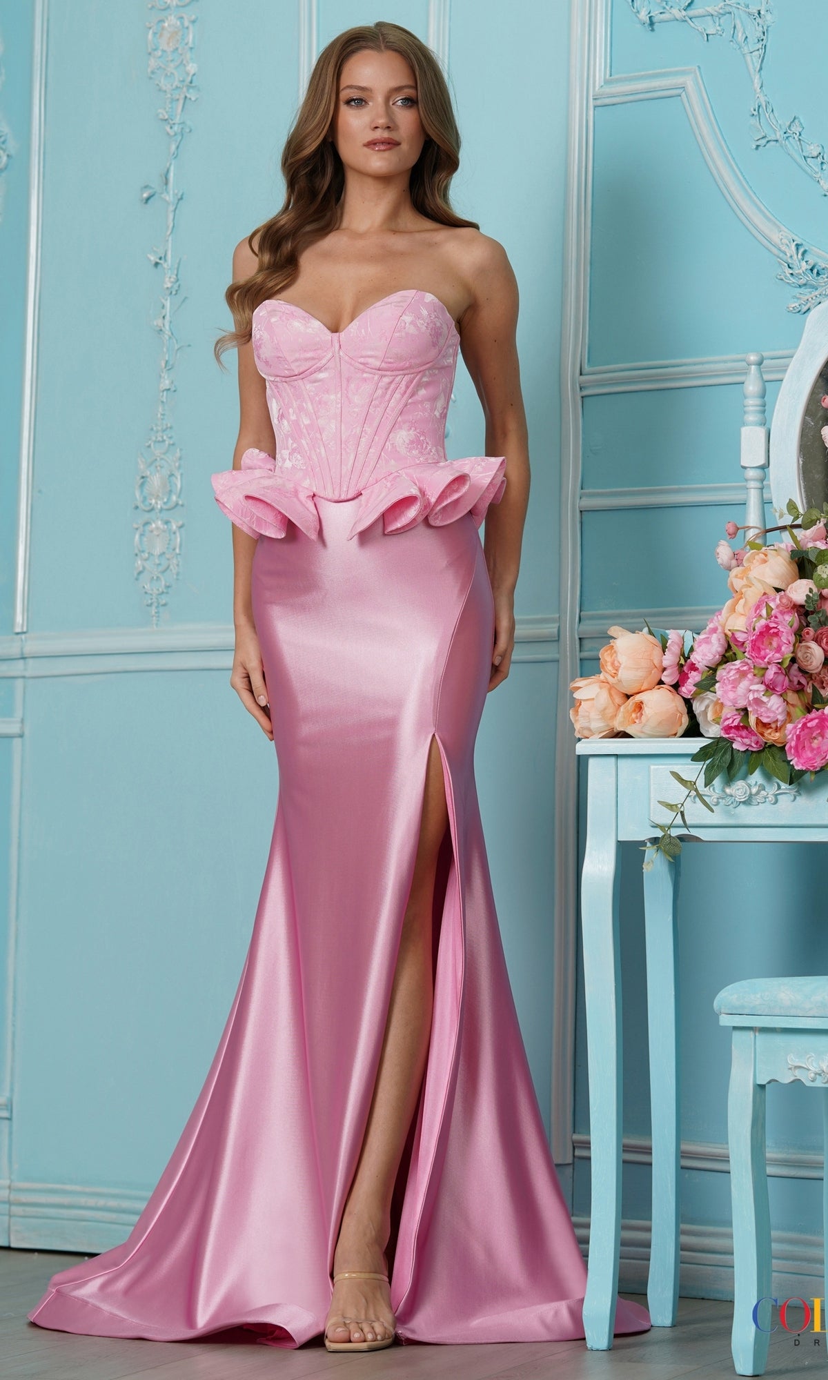Long Prom Dress: Colors Dress 4181 in pink, featuring a strapless corset design with a lace bodice, a ruffled peplum waist, and a side slit.