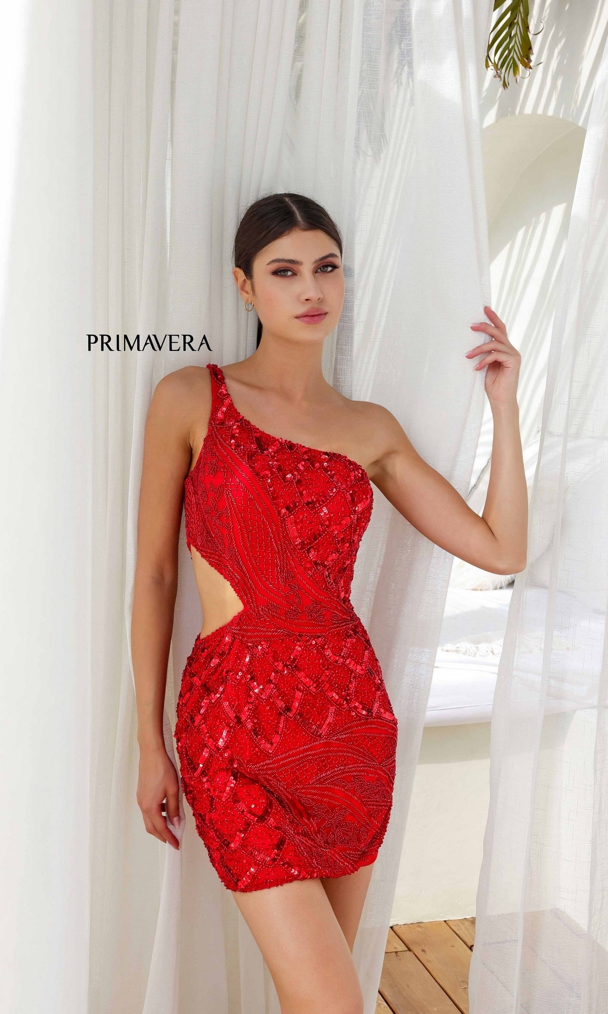 A woman in a red Cut-Out Short Beaded Hoco Dress: Primavera 4240 stands by white curtains with