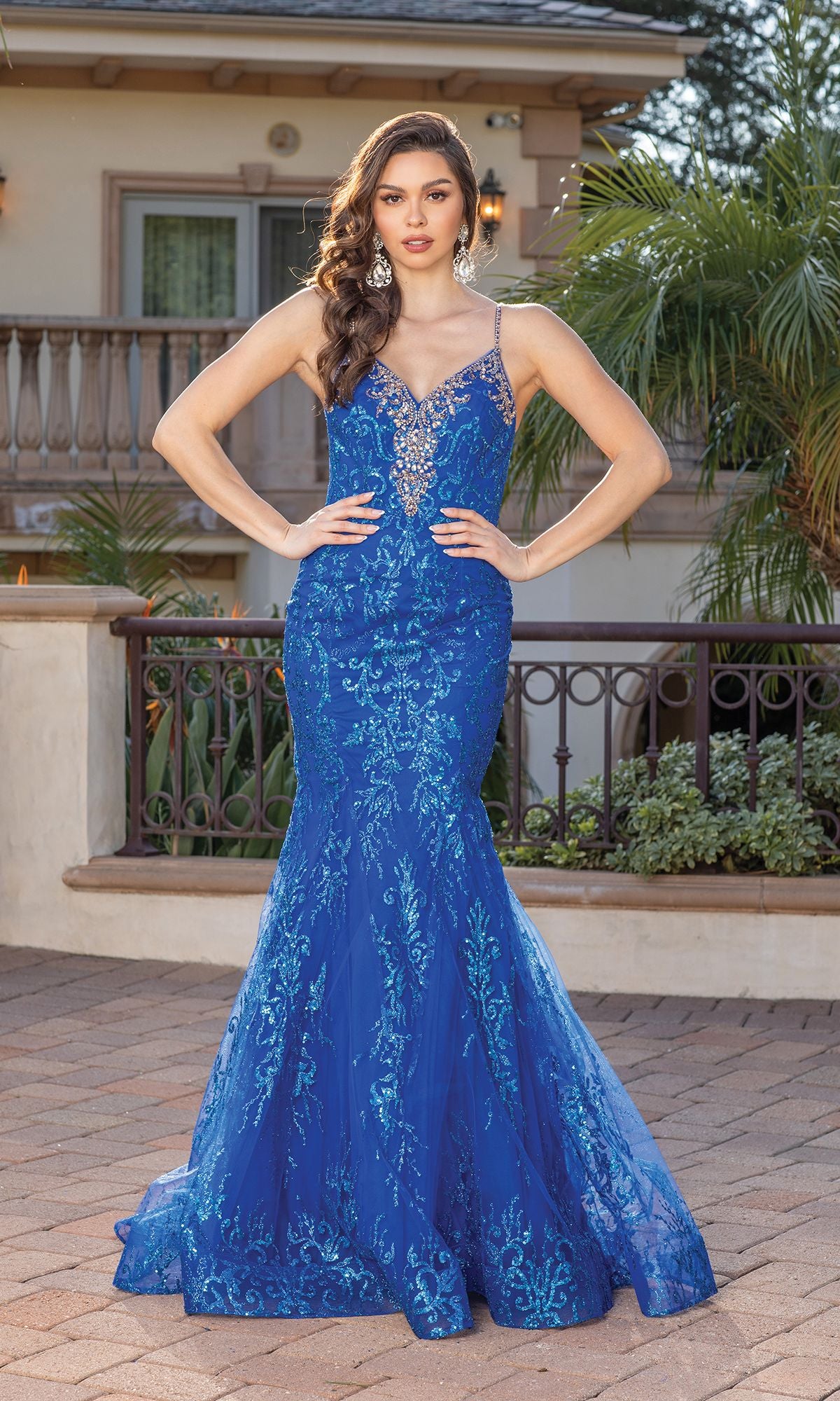 A woman stands outdoors with hands on hips, wearing the Sequin-Print Long Mermaid Prom Dress with Corset—fitted, royal blue, featuring thin straps and a v-neck.