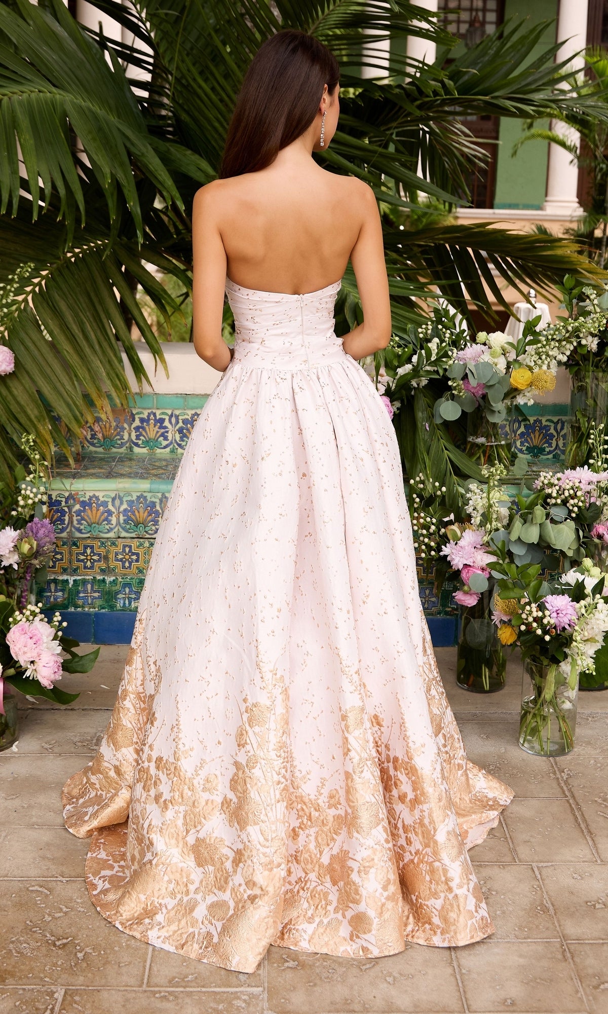 Back view of the Long Prom Dress: Ava Presley 42540, a strapless, floor-length light pink floral ball gown with a metallic gold pattern at the hem.