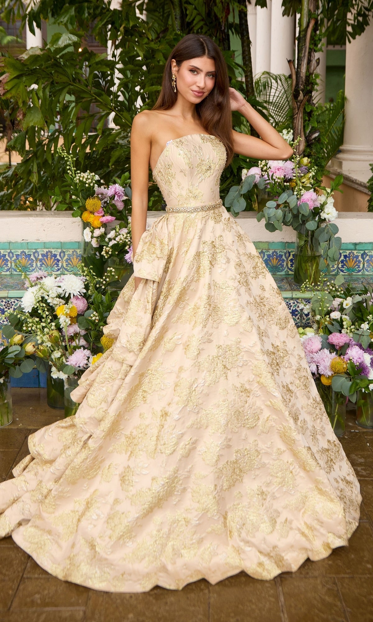 Long Prom Dress: Ava Presley 42555, a strapless, floor-length ball gown featuring an intricate gold floral pattern over a beige base with a thin embellished belt at the waist.