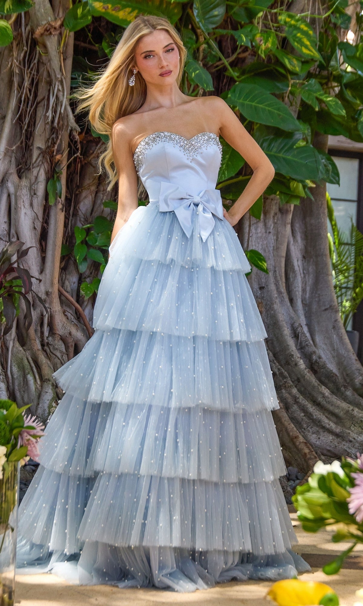 Light blue strapless Ava Presley 42589 ball gown with a crystal-embellished bodice, a waist bow, and a tiered tulle skirt accented with pearls.