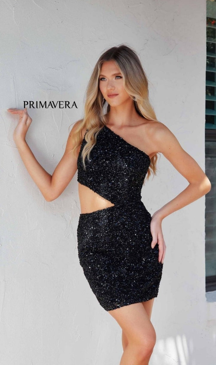 A woman poses against a white wall in the Cut-Out Short Sequin Hoco Dress: Primavera 4293, with