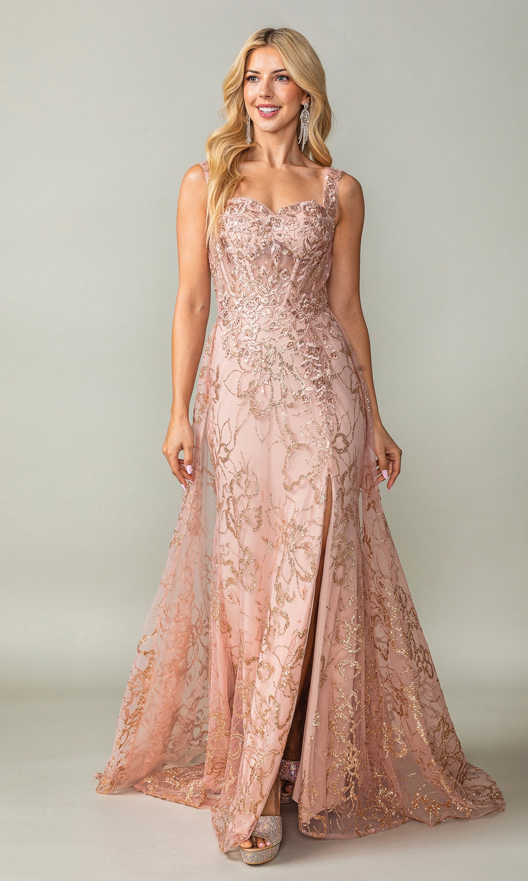 A woman stands wearing the Glitter-Print Lace-Up Long Prom Dress 4379, a floor-length blush pink A-line gown featuring gold embroidery and sequin details.