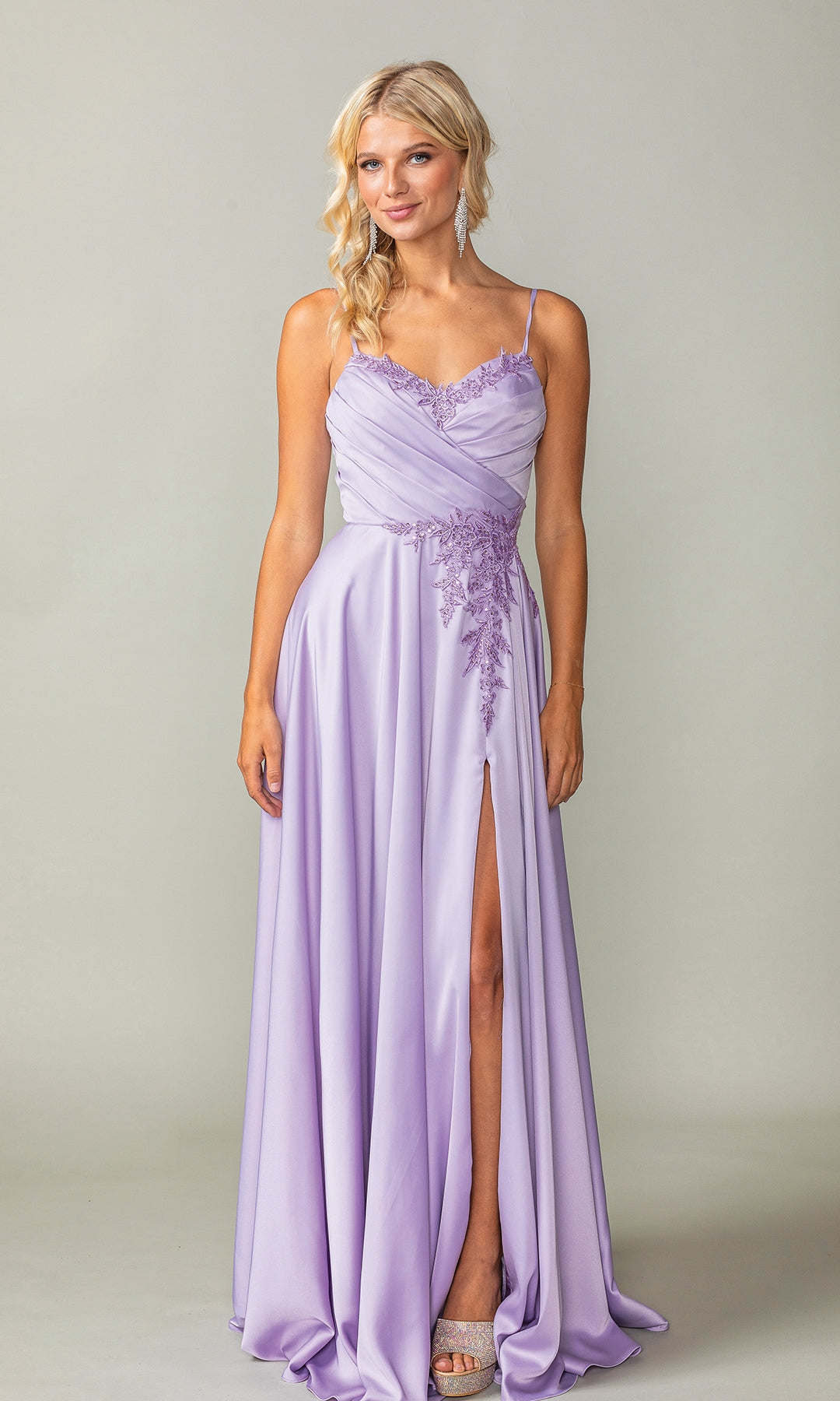 A woman wears the Lace-Up-Back Long A-Line Prom Dress 4391, featuring spaghetti straps, lace detailing, and a thigh-high slit, standing against a plain light background.