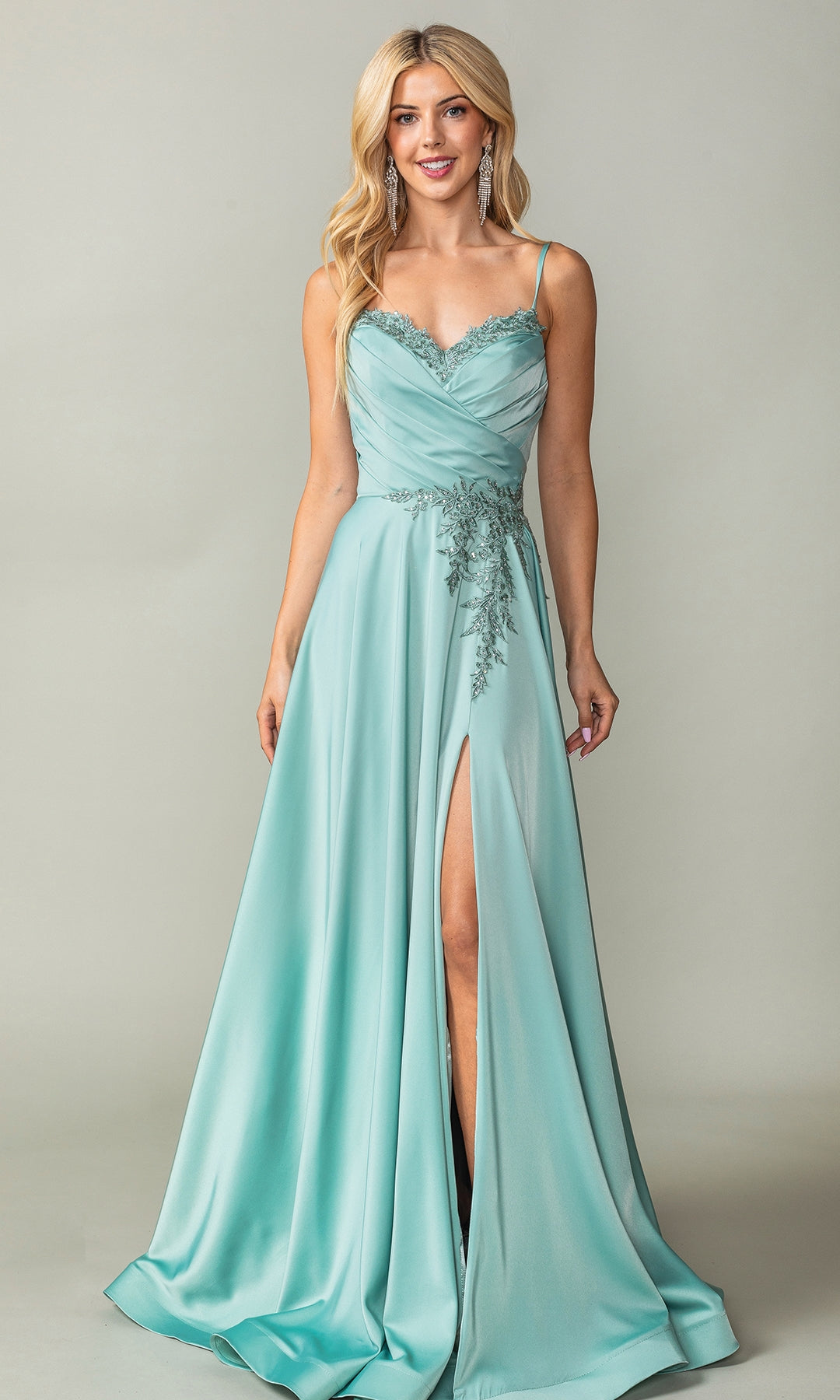 A woman poses against a plain background in the Lace-Up-Back Long A-Line Prom Dress 4391, featuring light teal fabric, thin straps, lace trim, a ruched bodice, thigh-high slit, and floral appliqué accents.