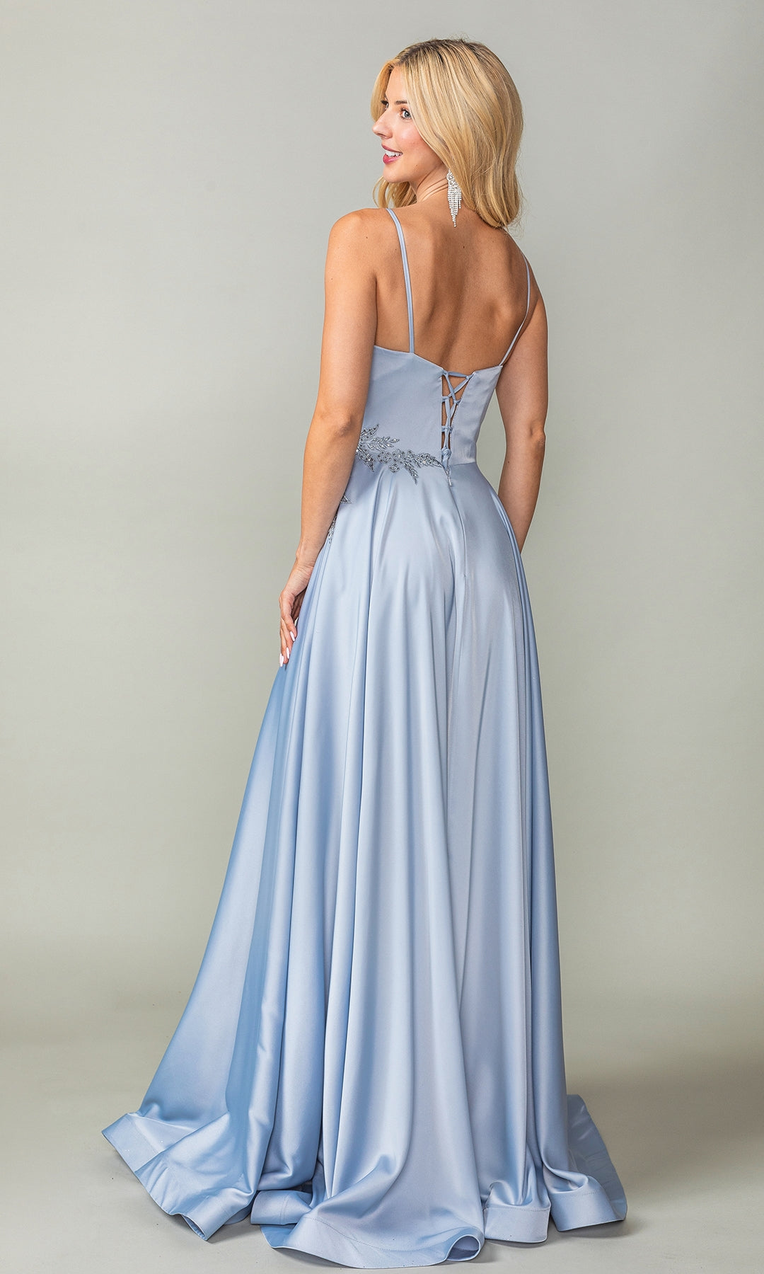 A woman stands facing away from the camera in the Lace-Up-Back Long A-Line Prom Dress 4391, featuring light blue satin fabric, thin straps, and a lace-up back detail.