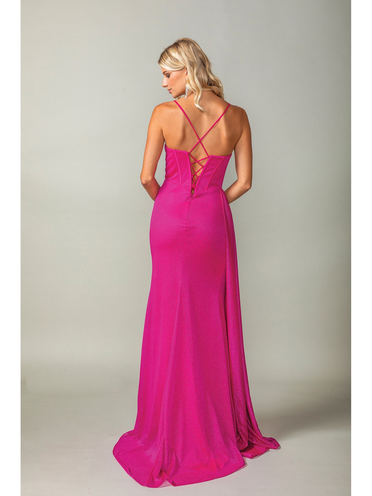 A woman stands with her back to the camera, wearing the Side-Drape Lace-Up Long Glitter Prom Dress 4399 in bright pink, featuring thin crisscross straps and a corset-style bodice against a plain background.