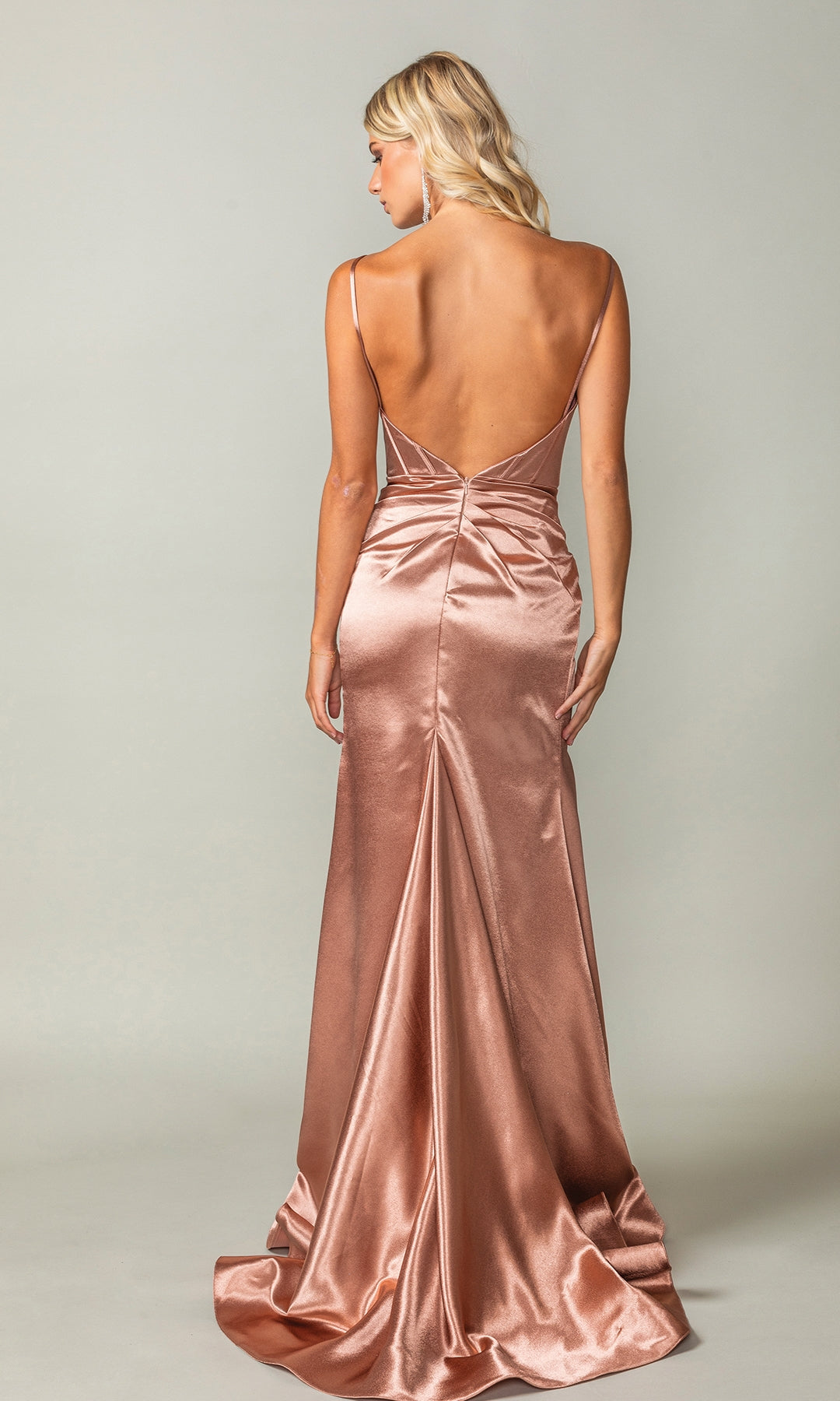 A woman in the Metallic Copper Long Prom Dress: Dancing Queen 4404 stands with her back to the camera, highlighting its low back, thin straps, fitted silhouette, and slight train.