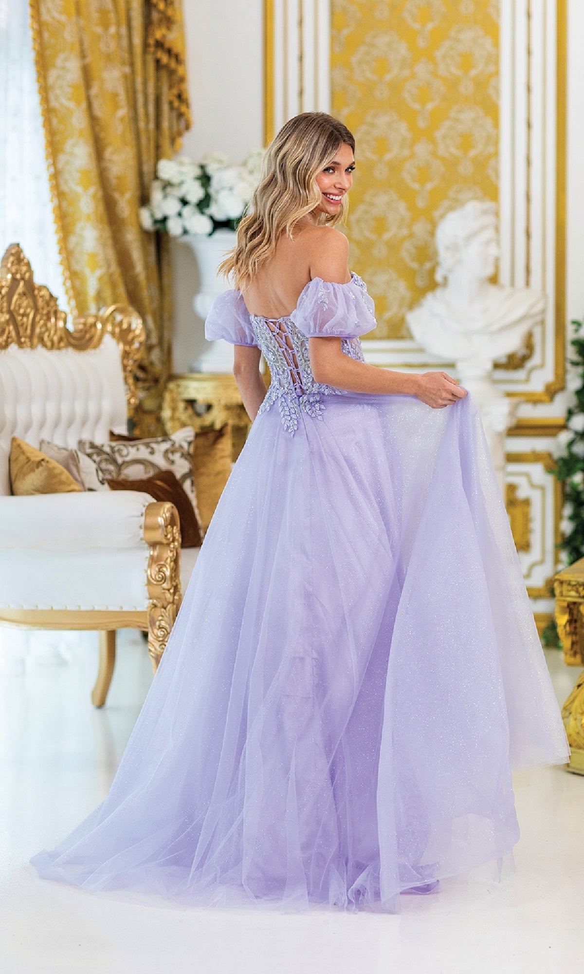 A woman in the Strapless Sweetheart Long Prom Dress 4406 stands in an ornate gold-accented room, looking over her shoulder and smiling.