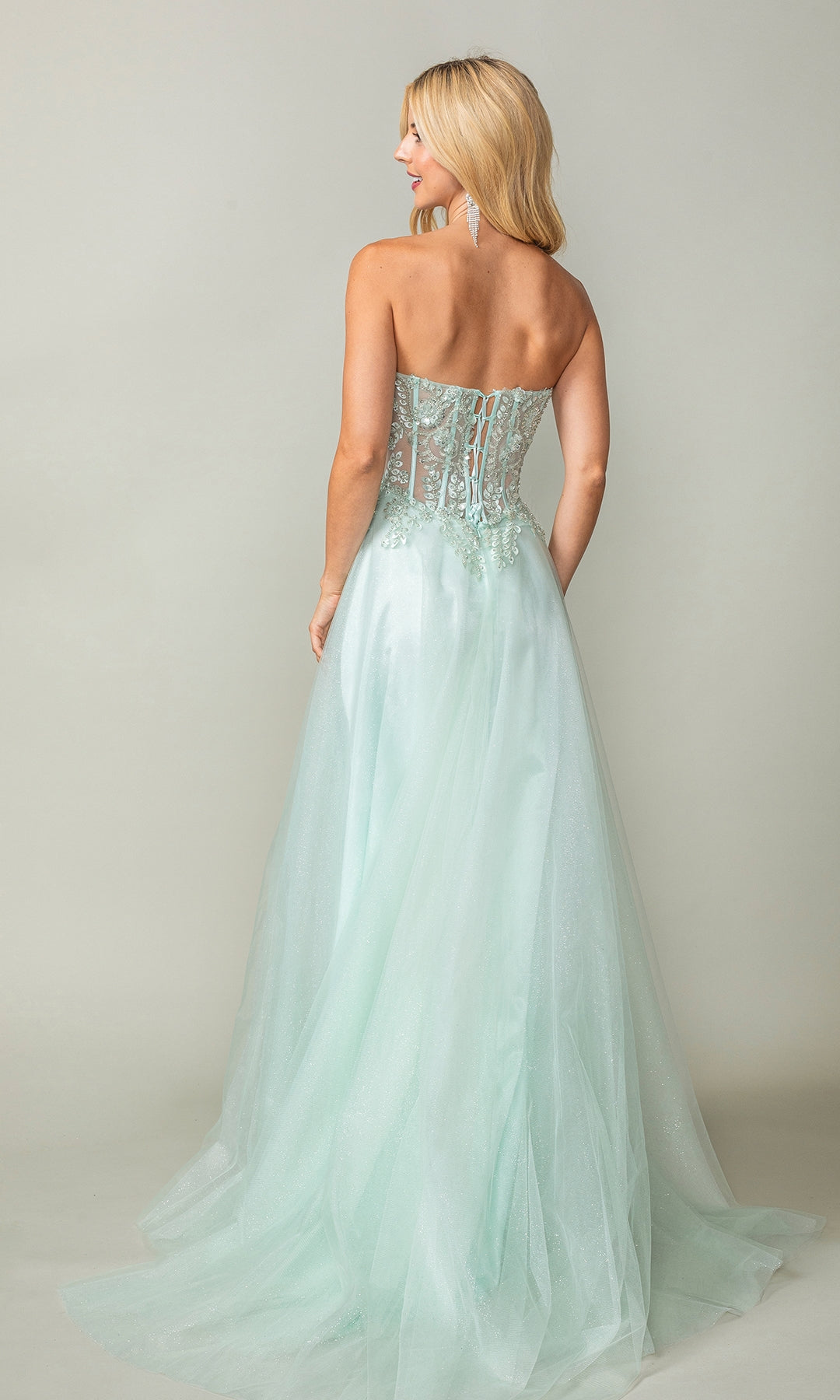 A woman faces away, wearing the Strapless Sweetheart Long Prom Dress 4406 in light green with an embroidered corset bodice and flowing tulle skirt.