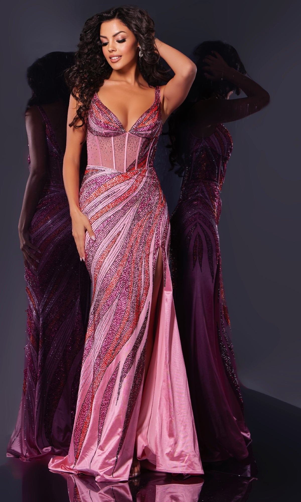 A woman poses in the Jovani 44577 long prom dress, a floor-length pink and purple sequined gown with multicolor beading and a thigh-high slit, against a reflective surface.