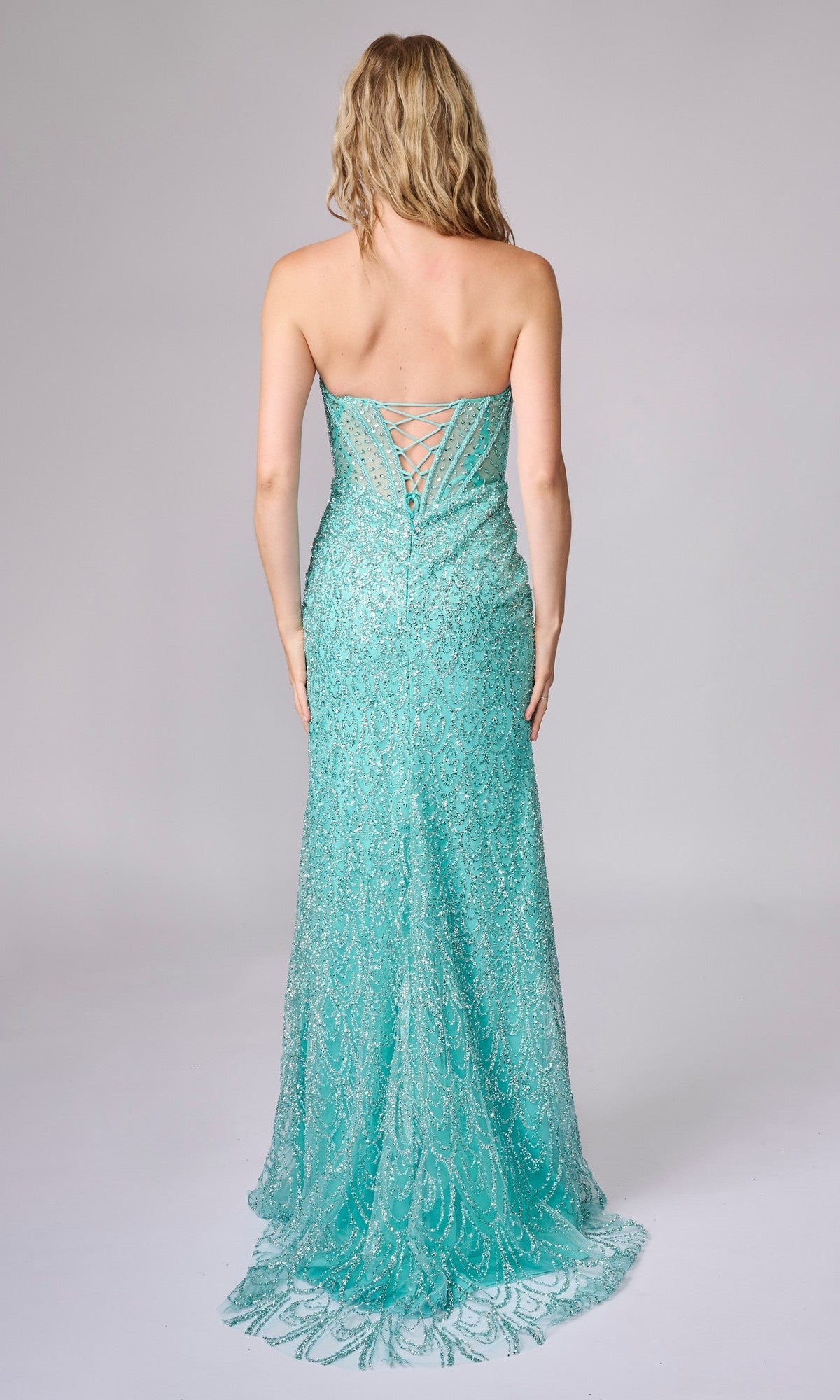 A woman models the Long Sequin Prom Dress: Nina Canacci 4458, featuring a strapless design with a sheer corset bodice and lace-up back, set against a plain background.