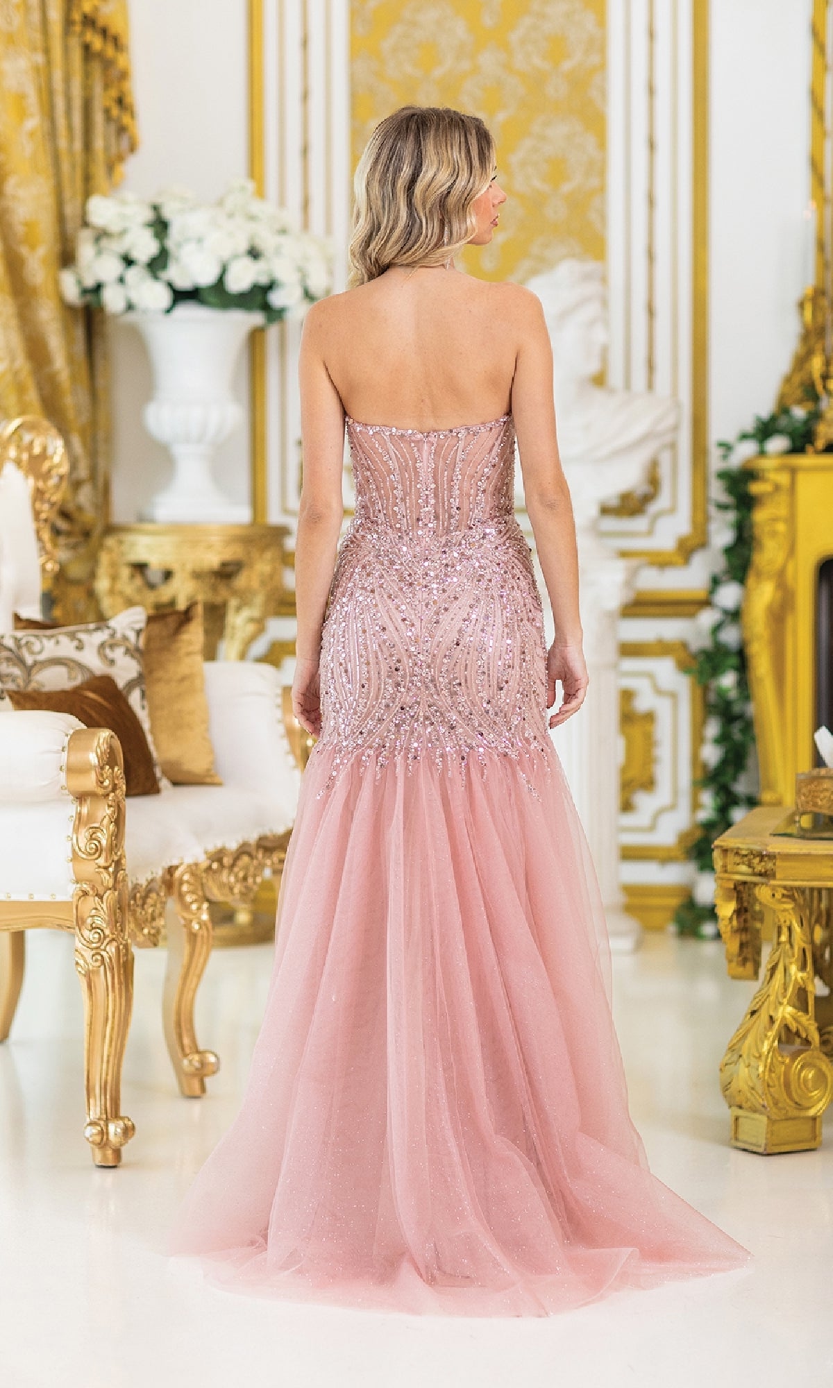 A woman in a Sequin-Bodice Long Prom Dress (Dancing Queen 4468) stands with her back to the camera in an ornate, gold-decorated room, her shimmering gown catching the light elegantly.