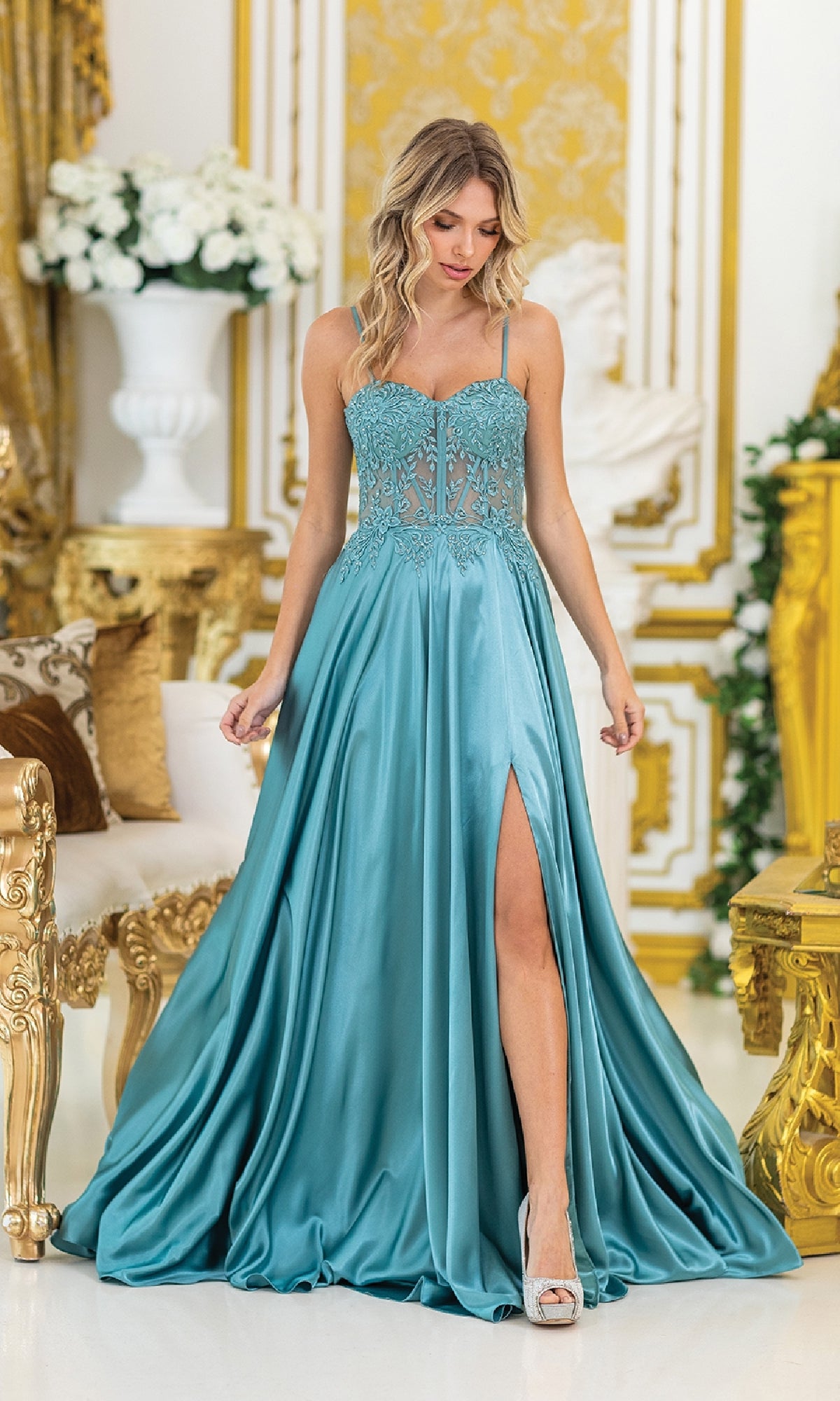 A woman in the Sheer-Waist Long Prom Dress: Dancing Queen 4520 stands in an ornate, gold-accented room with elegant white and gold furnishings.