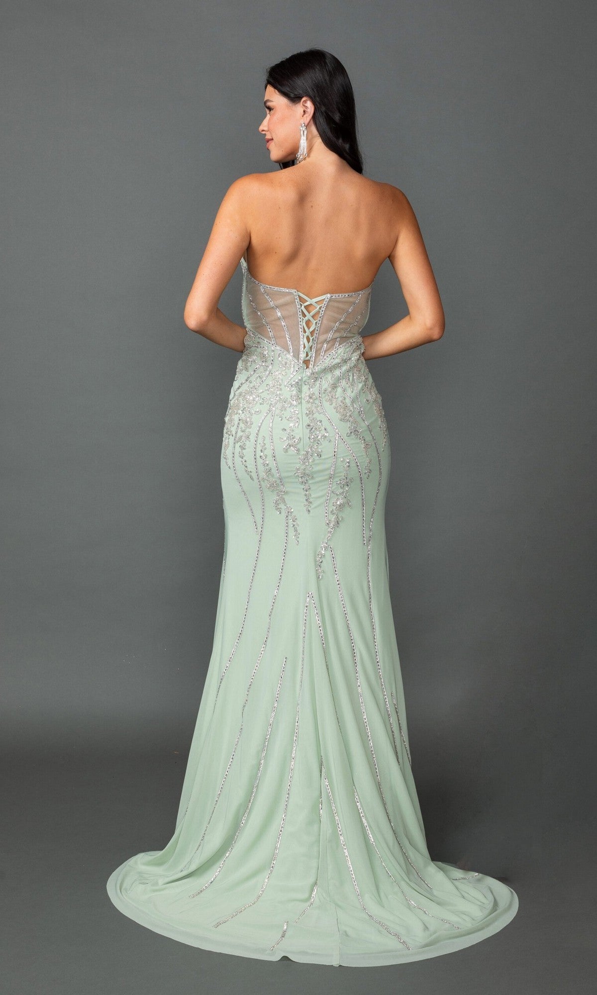 A woman stands against a plain gray background wearing the Long Prom Dress: Dancing Queen 4595โa mint green, floor-length strapless gown featuring a lace-up back, beaded applique embellishments, and a sheer panel.