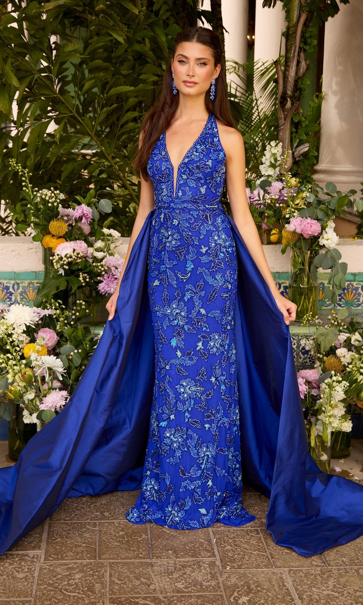 Royal blue Ava Presley 47421 halter-neck prom dress featuring a plunging neckline, intricate floral embroidery, and a detachable overskirt with an open-back design.