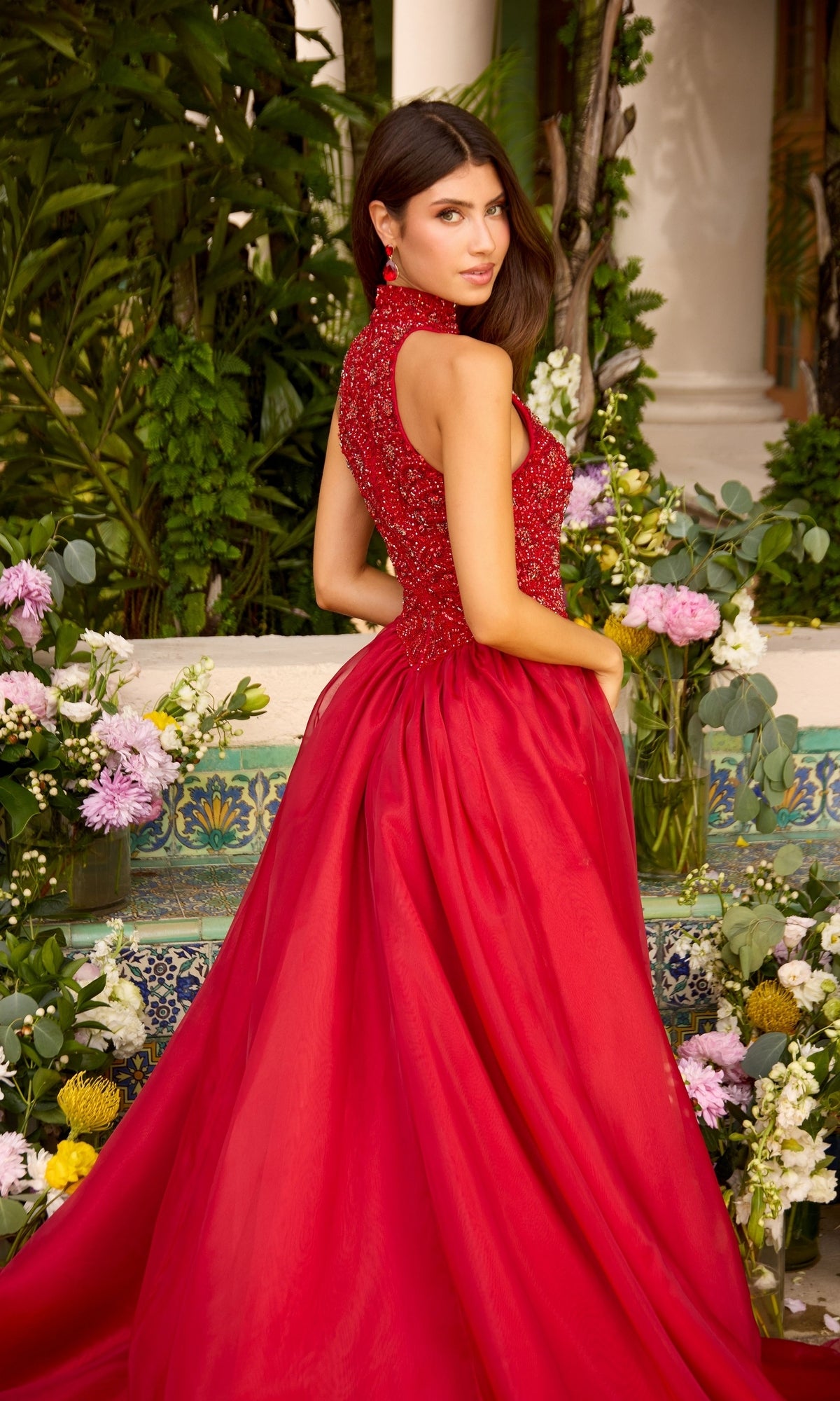 A woman wearing an Ava Presley 47425 red high-neck sleeveless gown with a beaded bodice and a full, flowing skirt.
