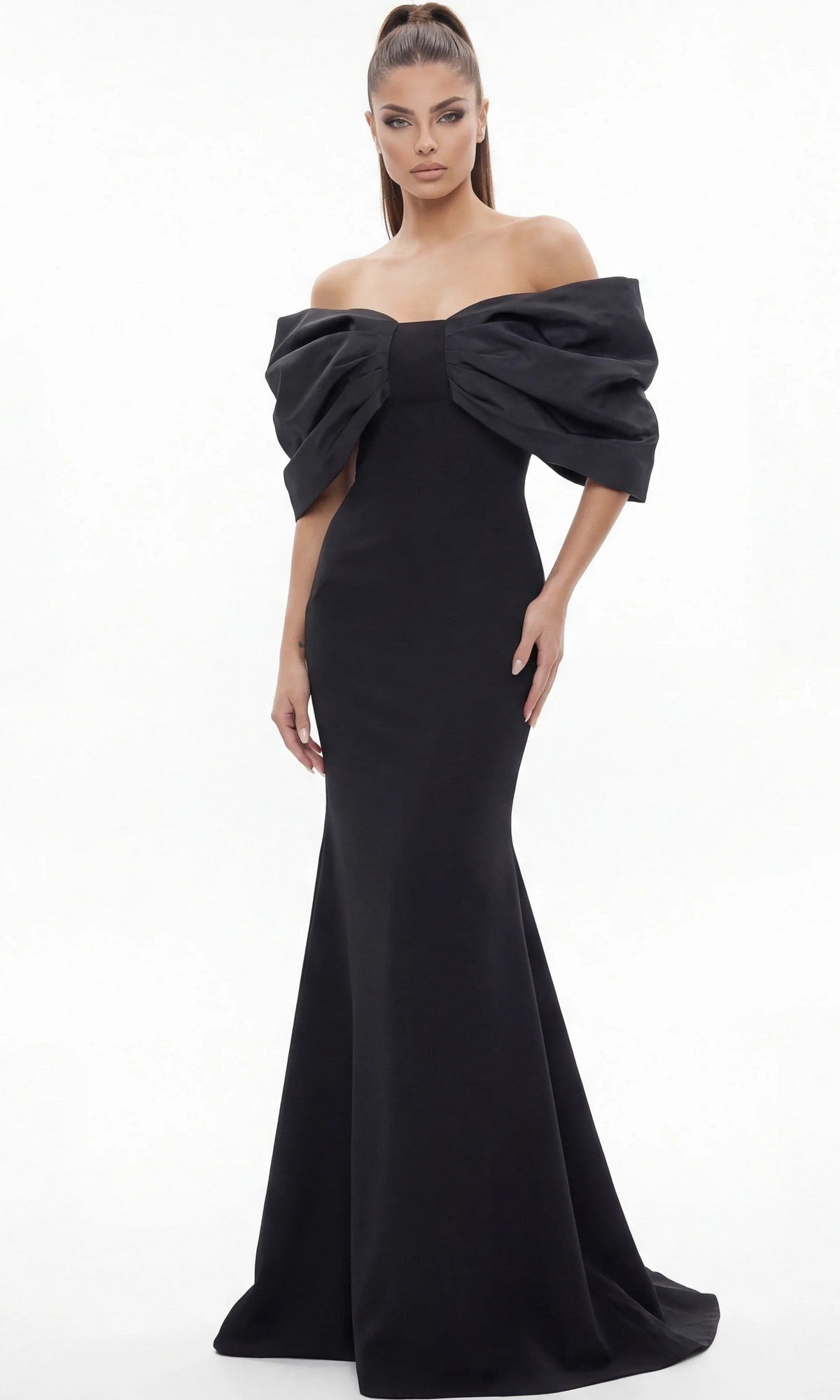 A woman stands against a white background wearing the Long Formal Dress: Jovani 47657, a floor-length, off-the-shoulder black gown featuring a dramatic structured bow detail on the bodice—an elegant designer piece ideal for any mother-of-the-bride.