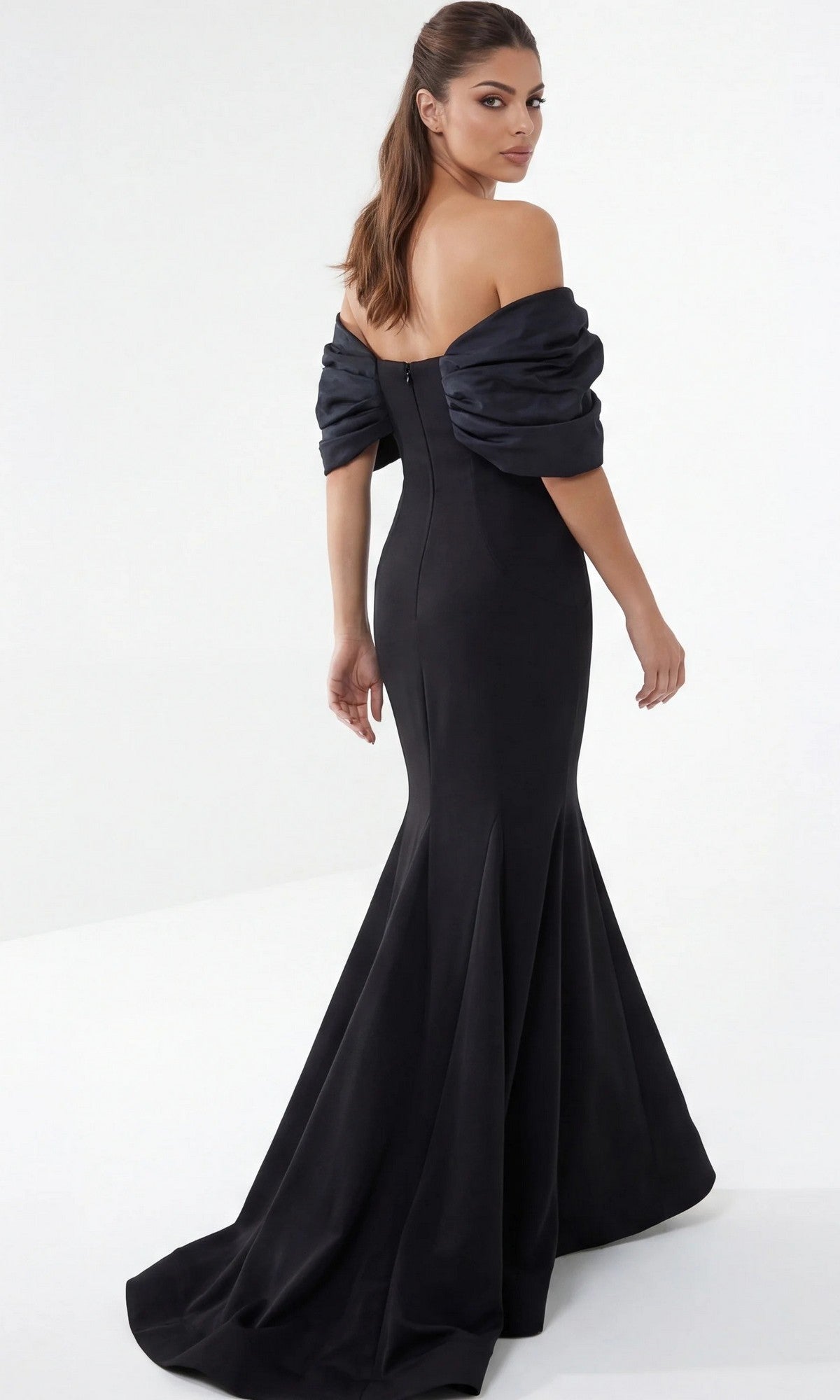 Woman in an off-the-shoulder, floor-length black Jovani 47657 long formal dress, standing and looking over her shoulder against a plain white background—a sophisticated choice for a designer gown or a modern mother-of-the-bride ensemble.
