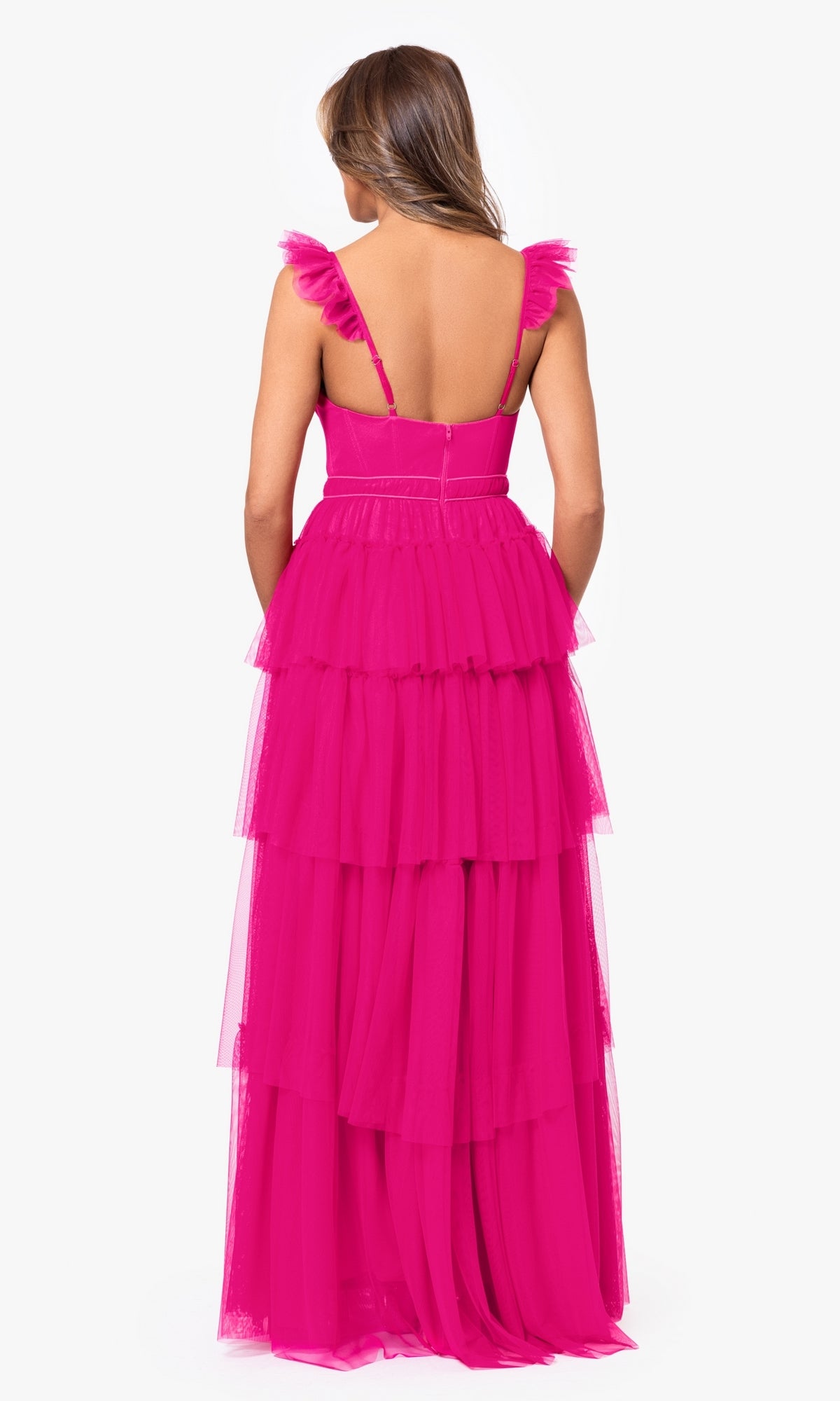 A woman faces away, wearing the Blondie Nites 4819BN Ruffled Tiered Long Prom Dress—bright pink, sleeveless, with tiered tulle layers, ruffled shoulder straps, and an open back.