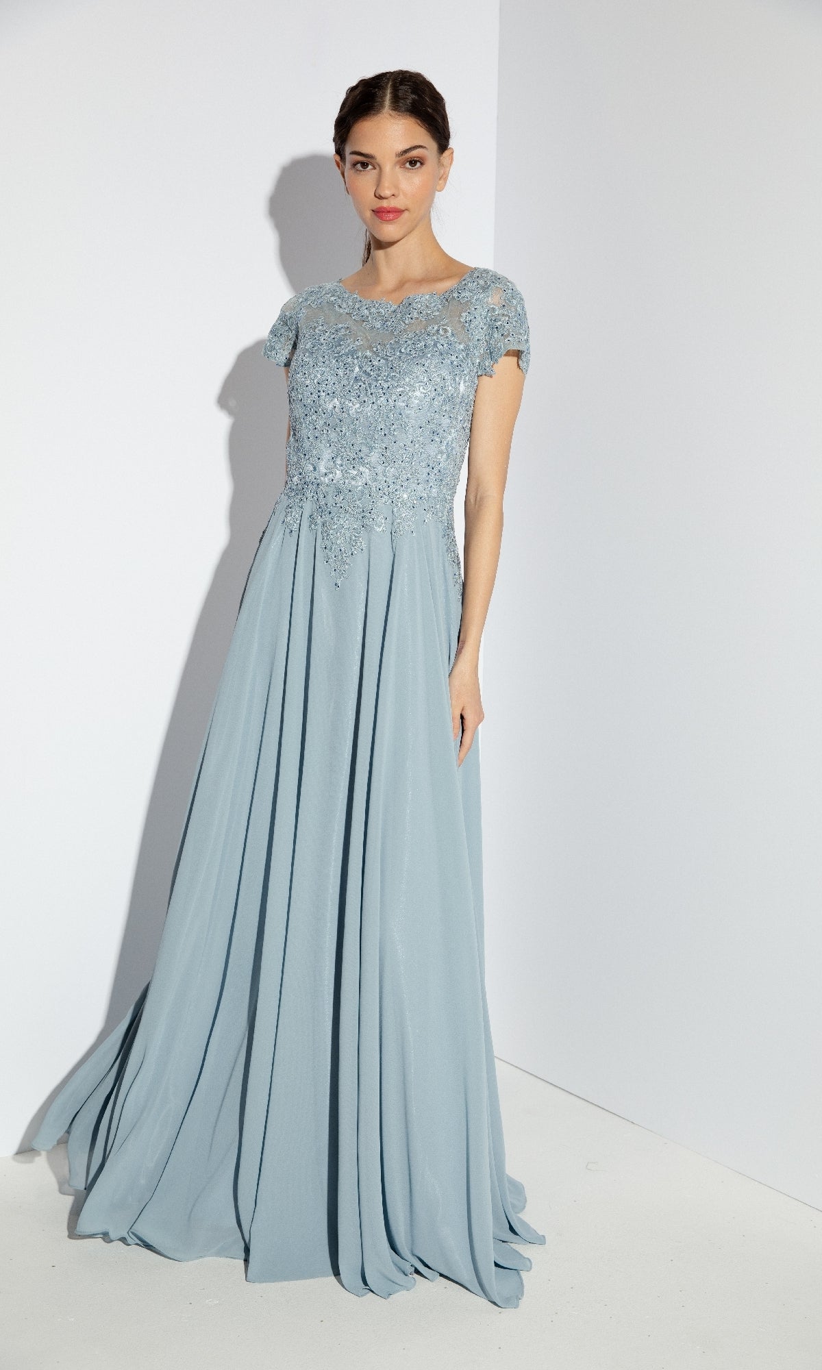 A woman wears the Eureka 4909, a short-sleeve long A-line formal dress, standing against a plain white background.