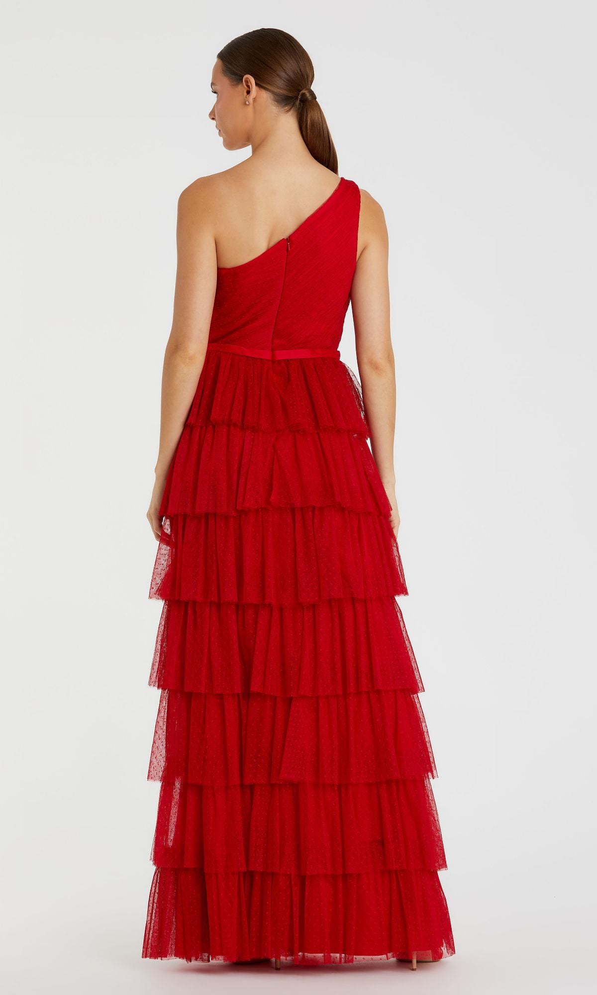 A woman models the Long Formal Dress 49102 by Mac Duggal, featuring a red one-shoulder design, tiered ruffle layers, and a banded waist, shown from the back against a plain background.