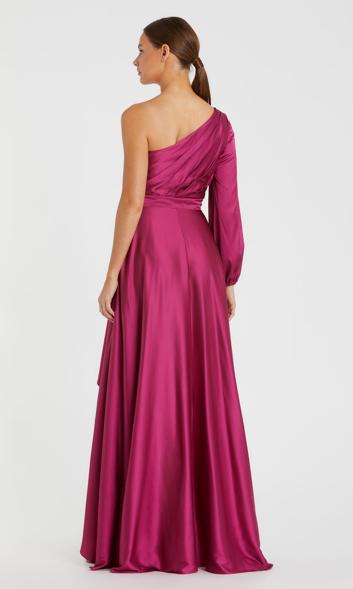 A woman stands with her back to the camera, wearing the Mac Duggal 49141 One-Sleeve High-Low Prom Dress in magenta satin, featuring an asymmetric neckline and a long, elegant silhouette.