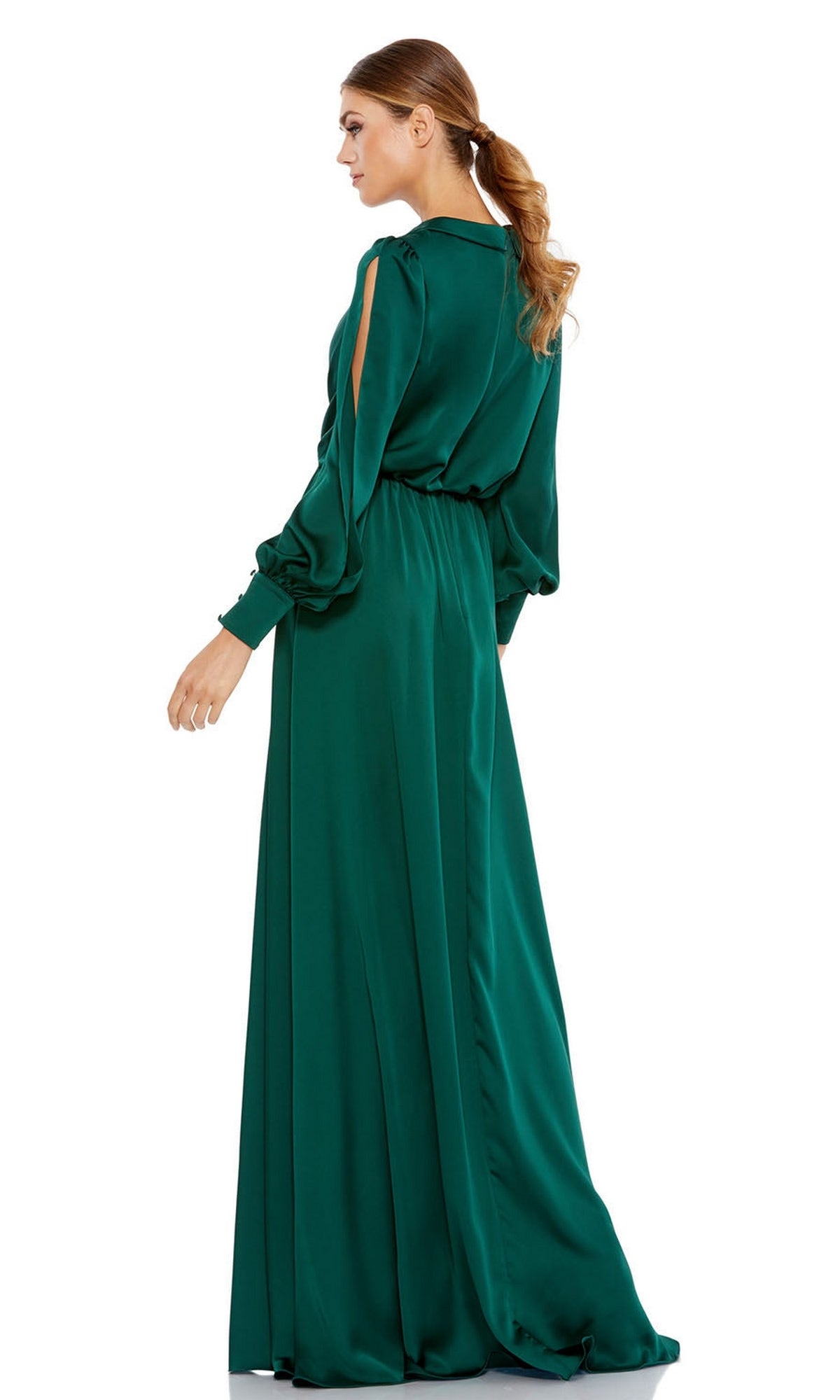 A woman stands gracefully facing away from the camera, wearing the Mac Duggal 49146 emerald green long formal dress with long sleeves and open sleeve details.