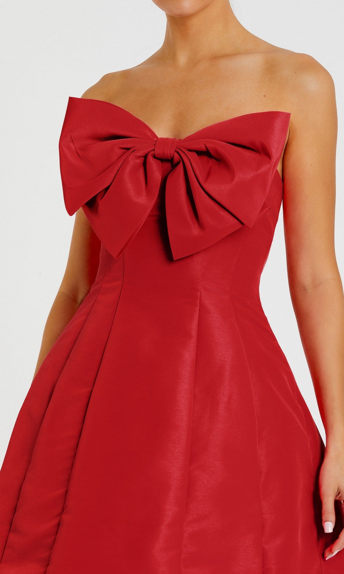 A woman wears the Mac Duggal 49210 Strapless Short Bow Party Dress in vibrant red, showcasing a bold bow detail at the chest for an elegant semi-formal style.