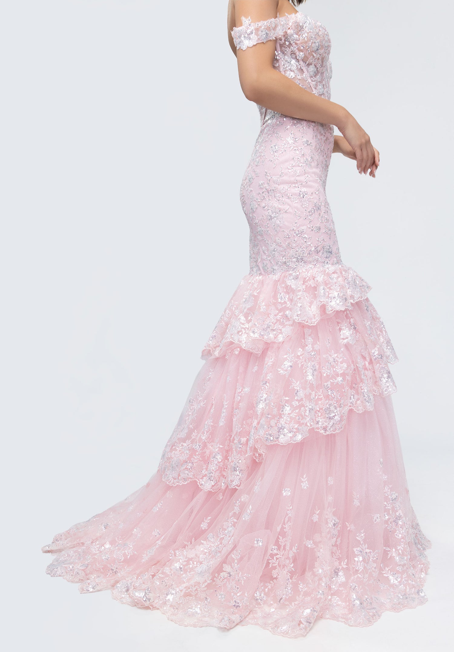 Woman wearing Morilee 49274, a light pink off-shoulder lace corset gown featuring sequin details and a layered ruffle skirt.
